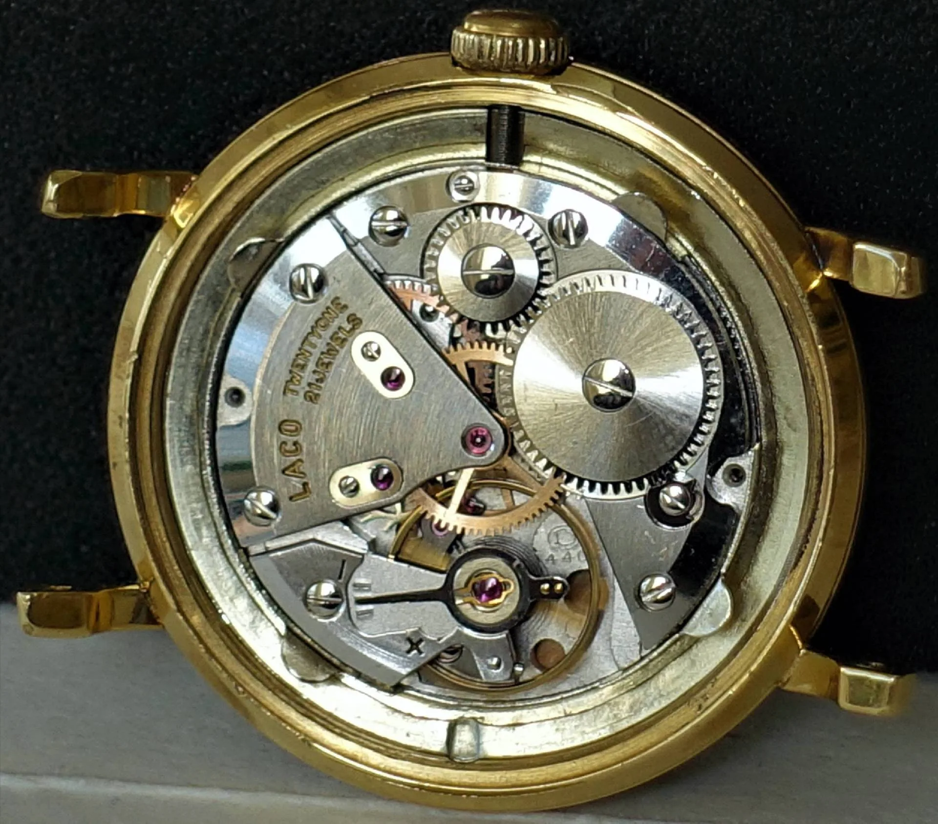 Mechanisches Uhrwerk in einem goldfarbenen Gehäuse mit sichtbaren Zahnrädern und Schrauben.