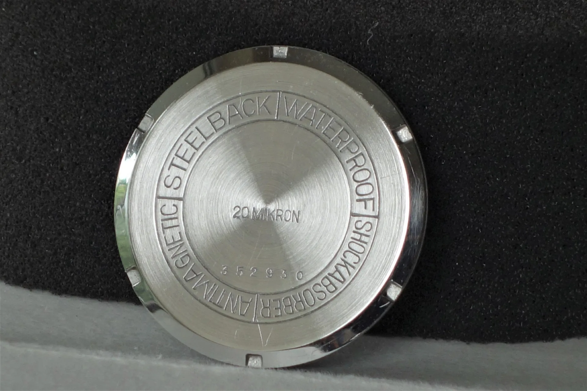 Silberfarbener runder Uhrboden mit Gravur und satinierter Oberfläche.