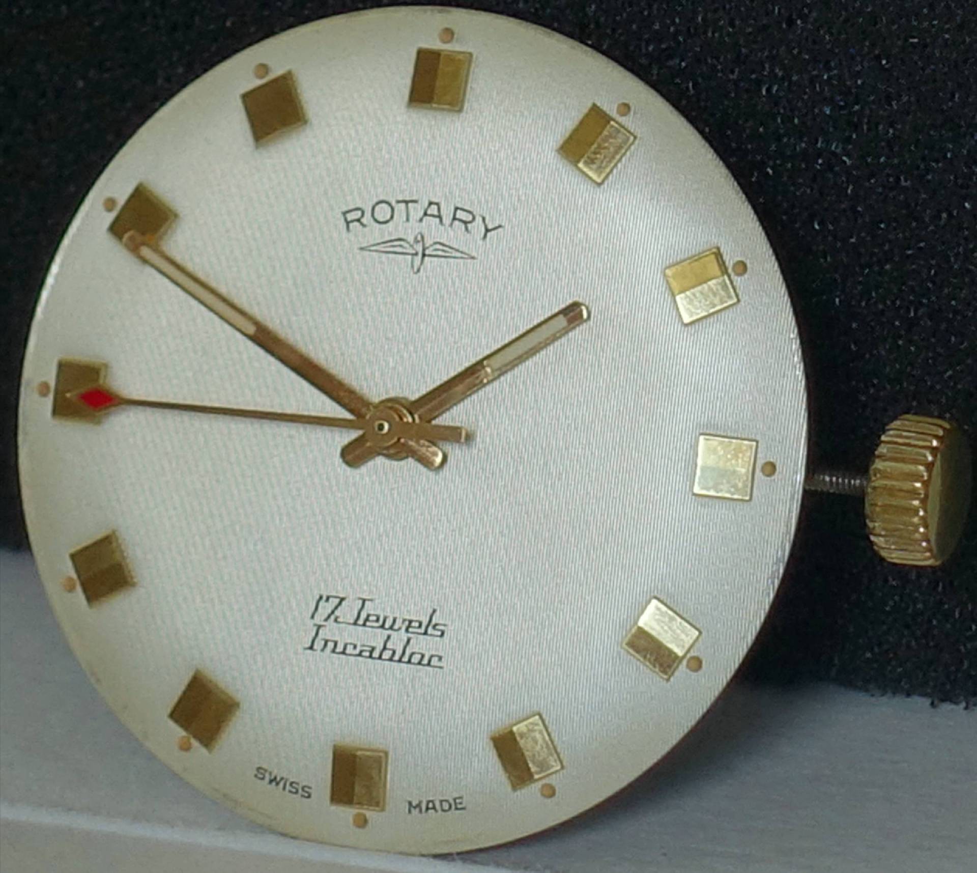 Rundes Zifferblatt einer Vintage-Armbanduhr der Marke Rotary mit goldenen Indizes, Zeigern und seitlicher Aufzugskrone.