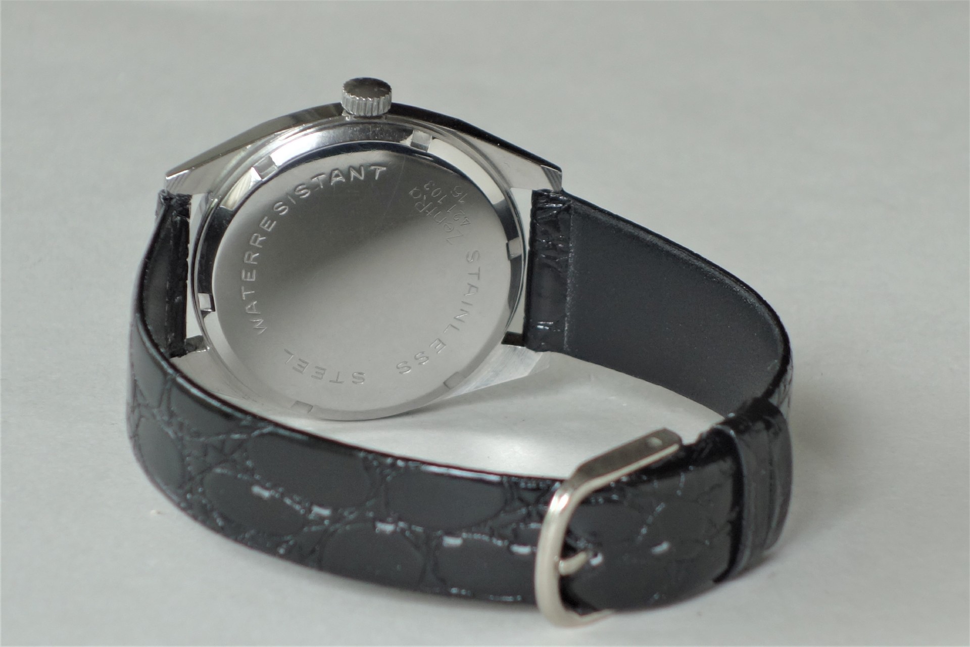 Armbanduhr mit schwarzem Armband und silberfarbener Rückseite.