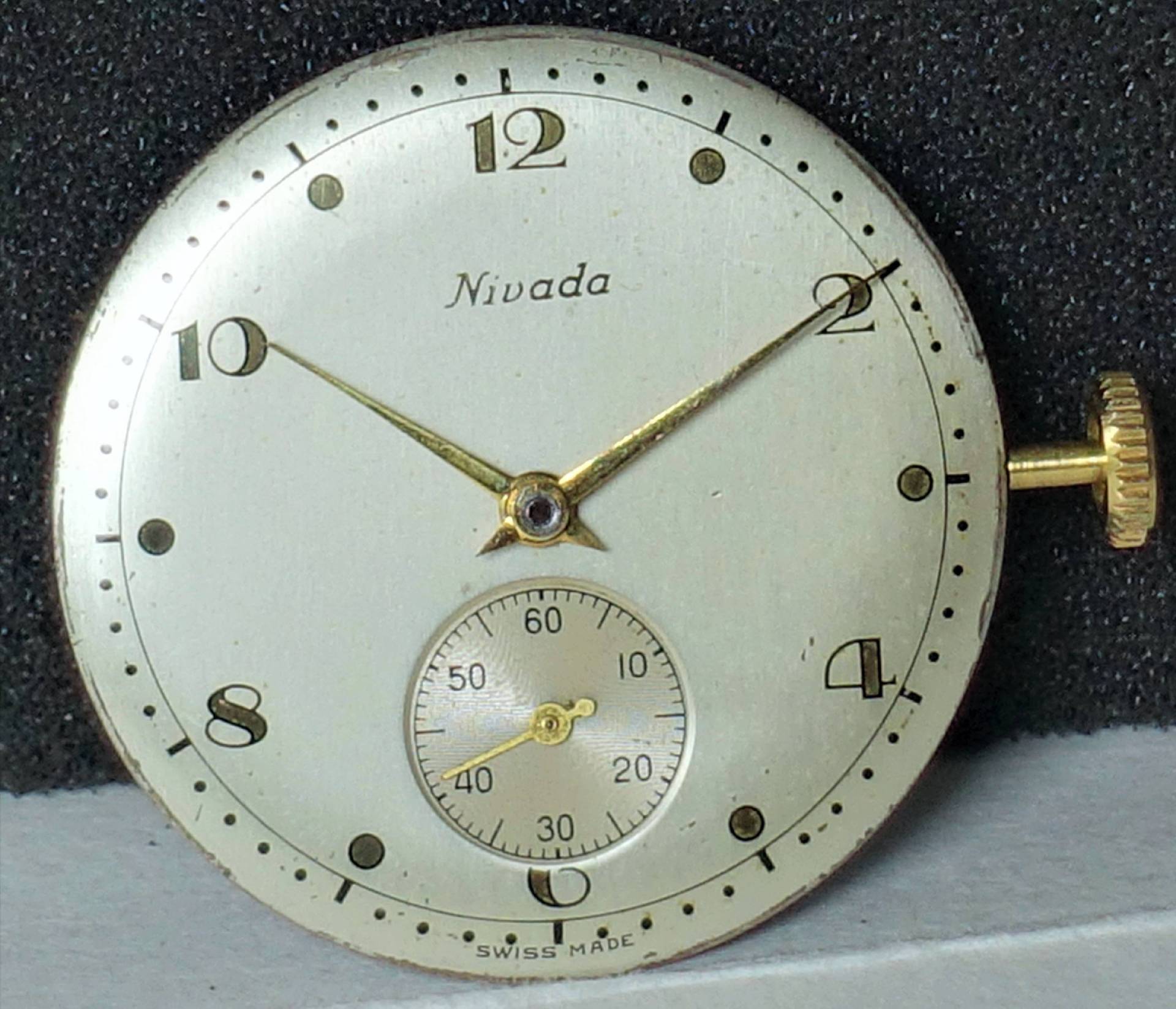 Rundes silberfarbenes Uhrwerk mit Zifferblatt, goldfarbenen Zeigern und kleiner Sekunde.