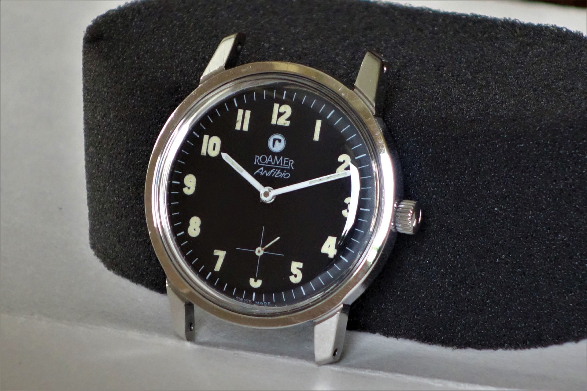 Schwarze Armbanduhr mit silberfarbenem Gehäuse und weißen Zeigern.