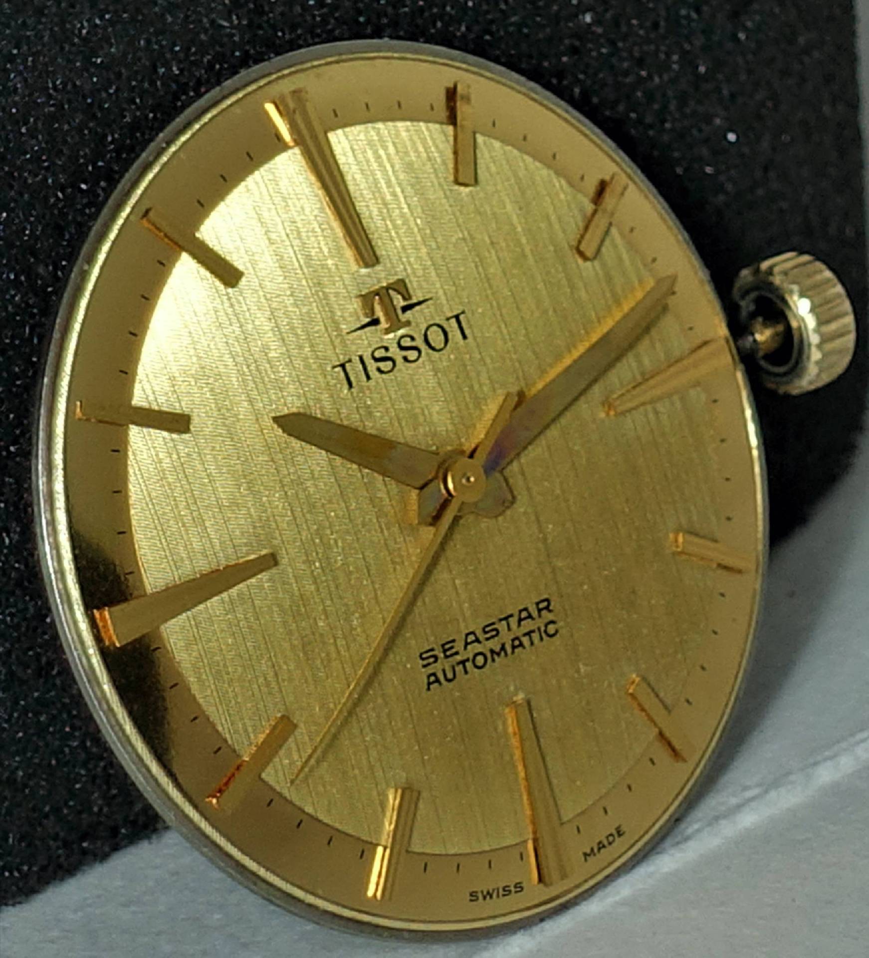Goldenes Zifferblatt mit goldfarbenen Zeigern und Indizes, Aufschrift "Tissot Seastar Automatic".