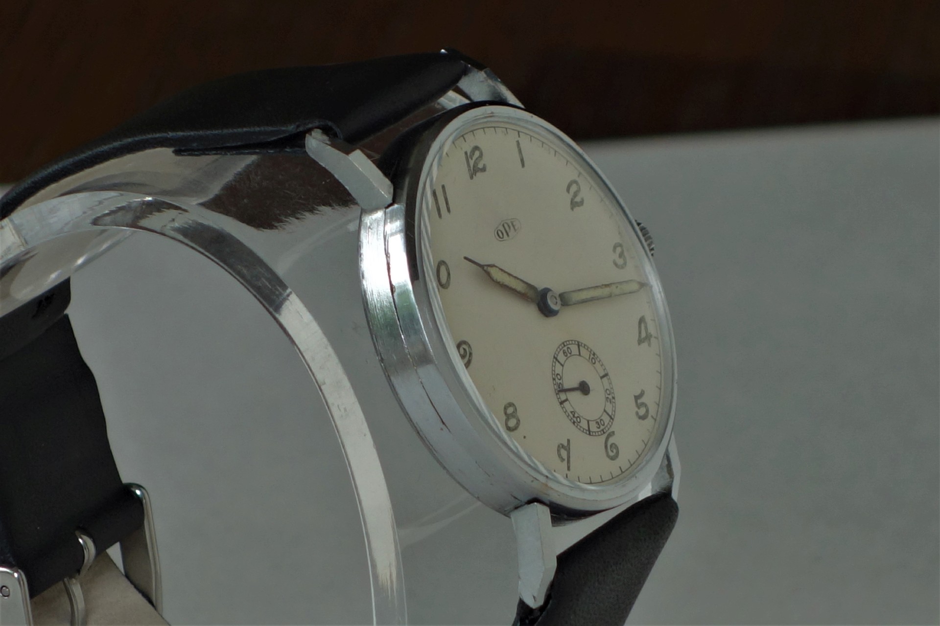 Analoge Armbanduhr mit cremefarbenem Zifferblatt, silberfarbenem Gehäuse und schwarzem Armband.