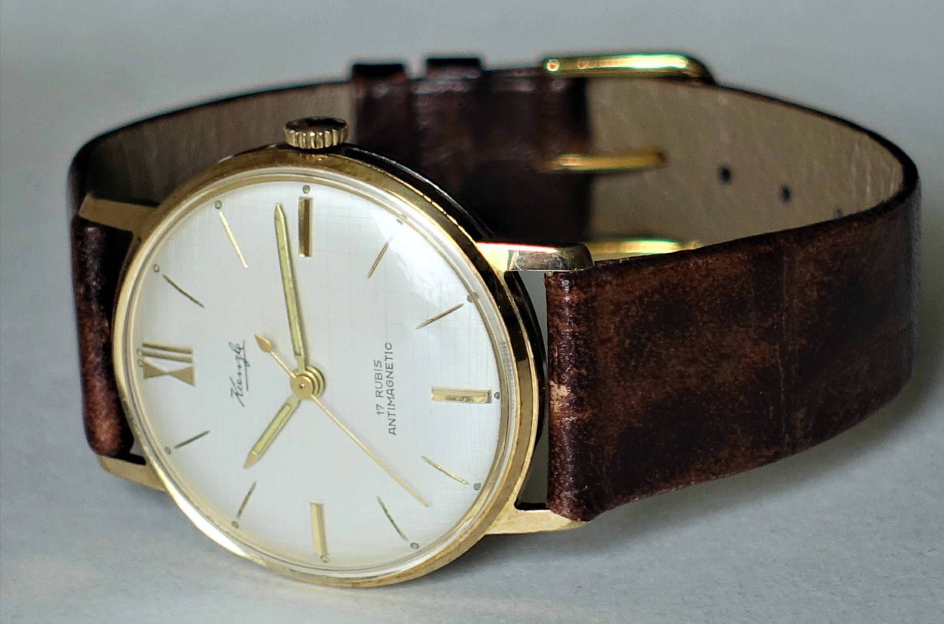 Klassische Armbanduhr mit goldfarbenem Gehäuse und braunem Lederarmband.
