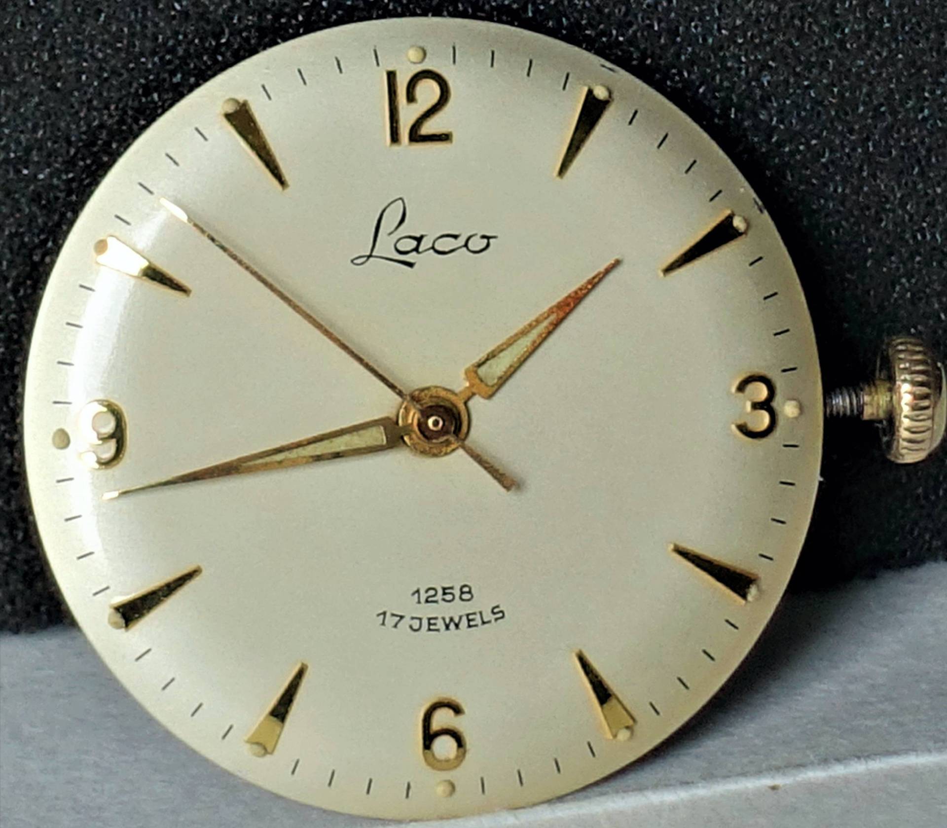 Rundes Laco Uhrwerk mit cremefarbenem Zifferblatt, goldfarbenen Zeigern und goldfarbenen Indizes.
