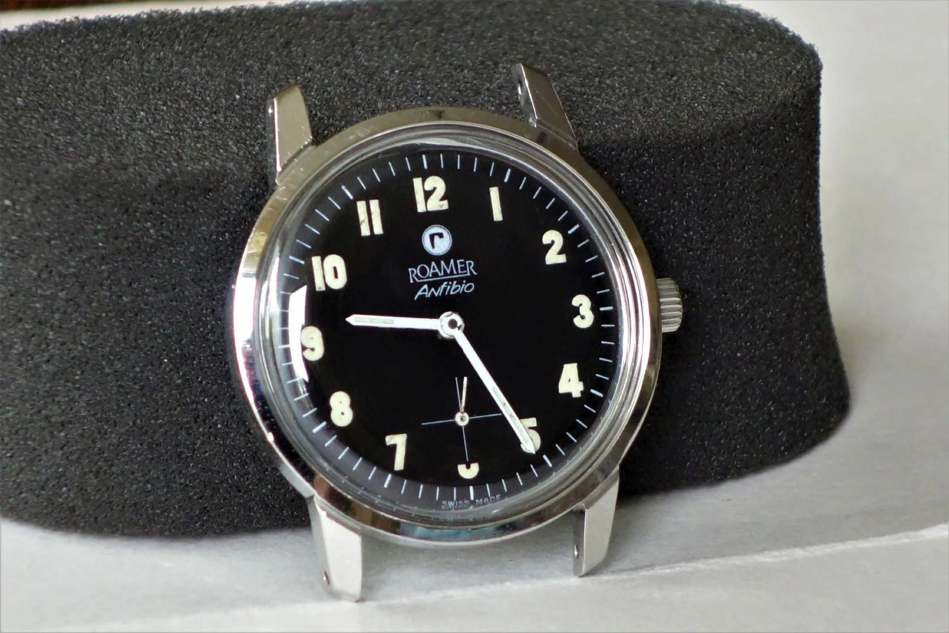 Schwarze Armbanduhr mit silberfarbenem Gehäuse und Leuchtziffern, Modell Roamer Anfibio.