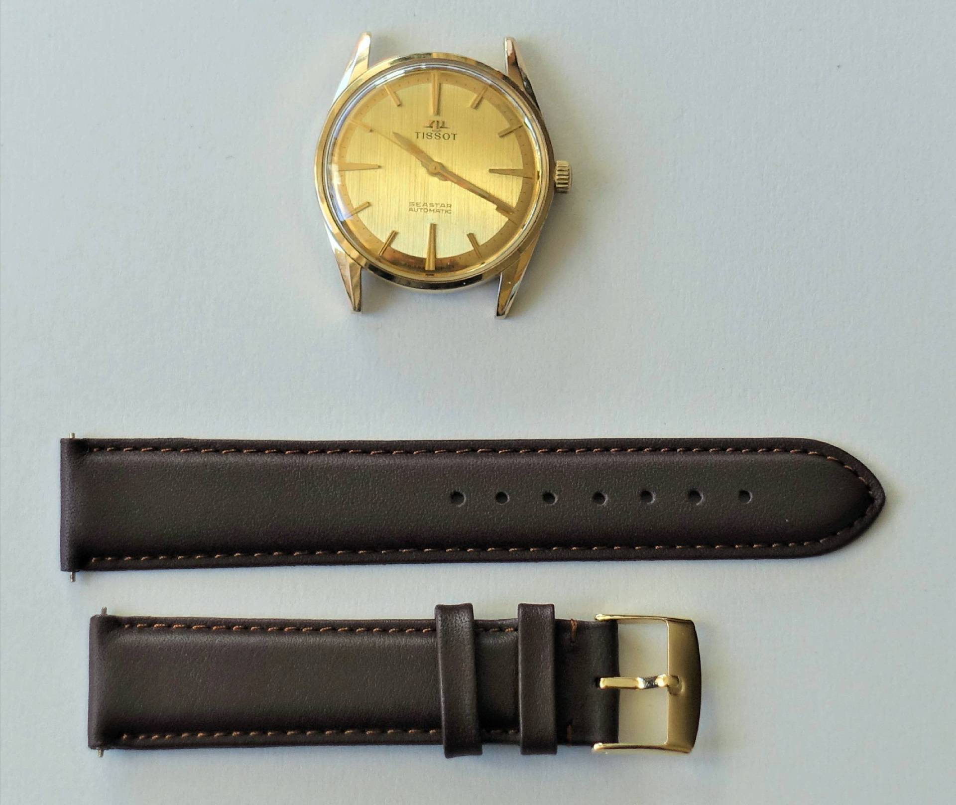 Goldfarbene Tissot Armbanduhr mit braunem Lederarmband und goldfarbener Schließe.