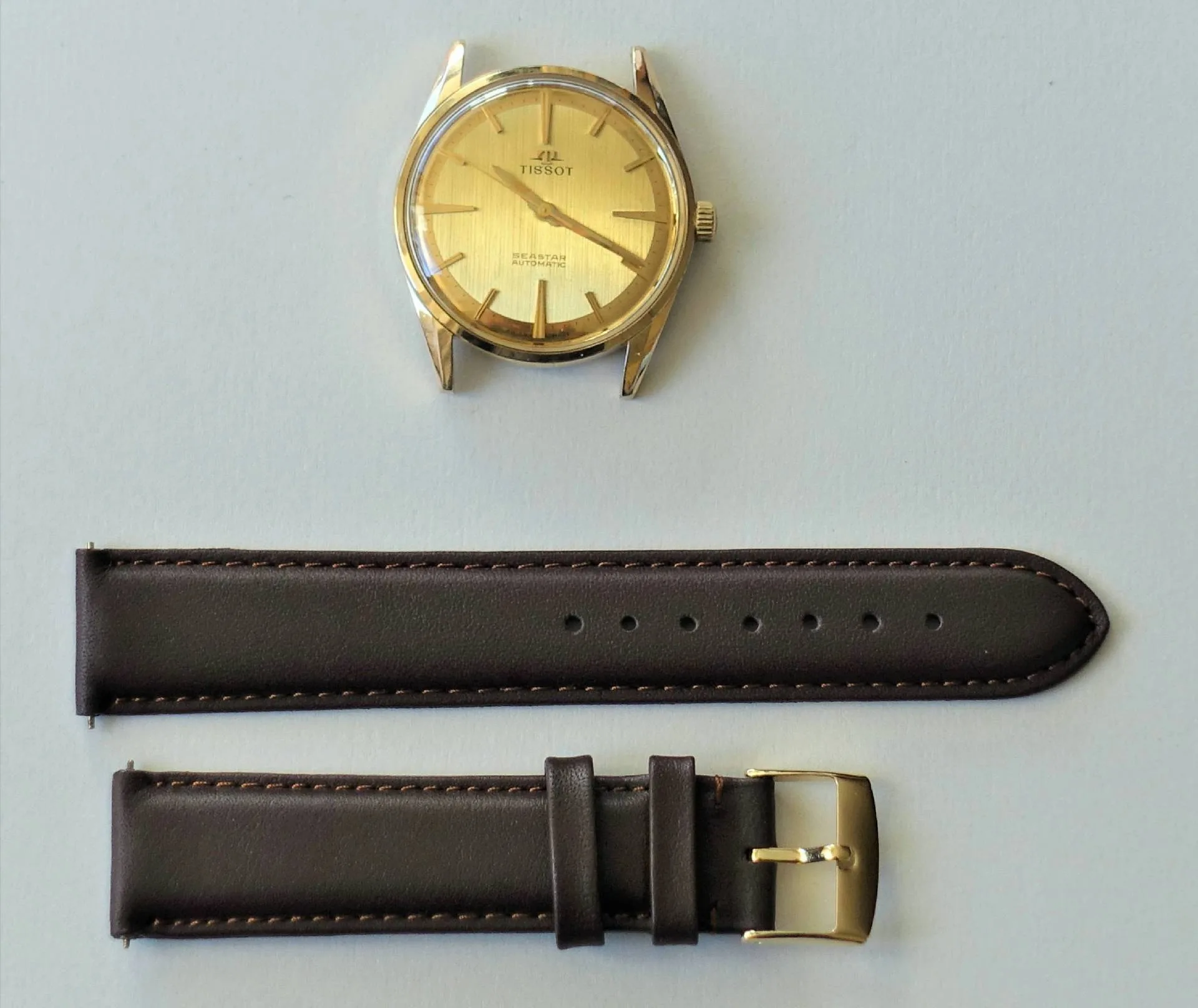 Tissot Armbanduhr goldfarben Goldfarbene Tissot Armbanduhr mit braunem Lederarmband und goldfarbener Schließe.