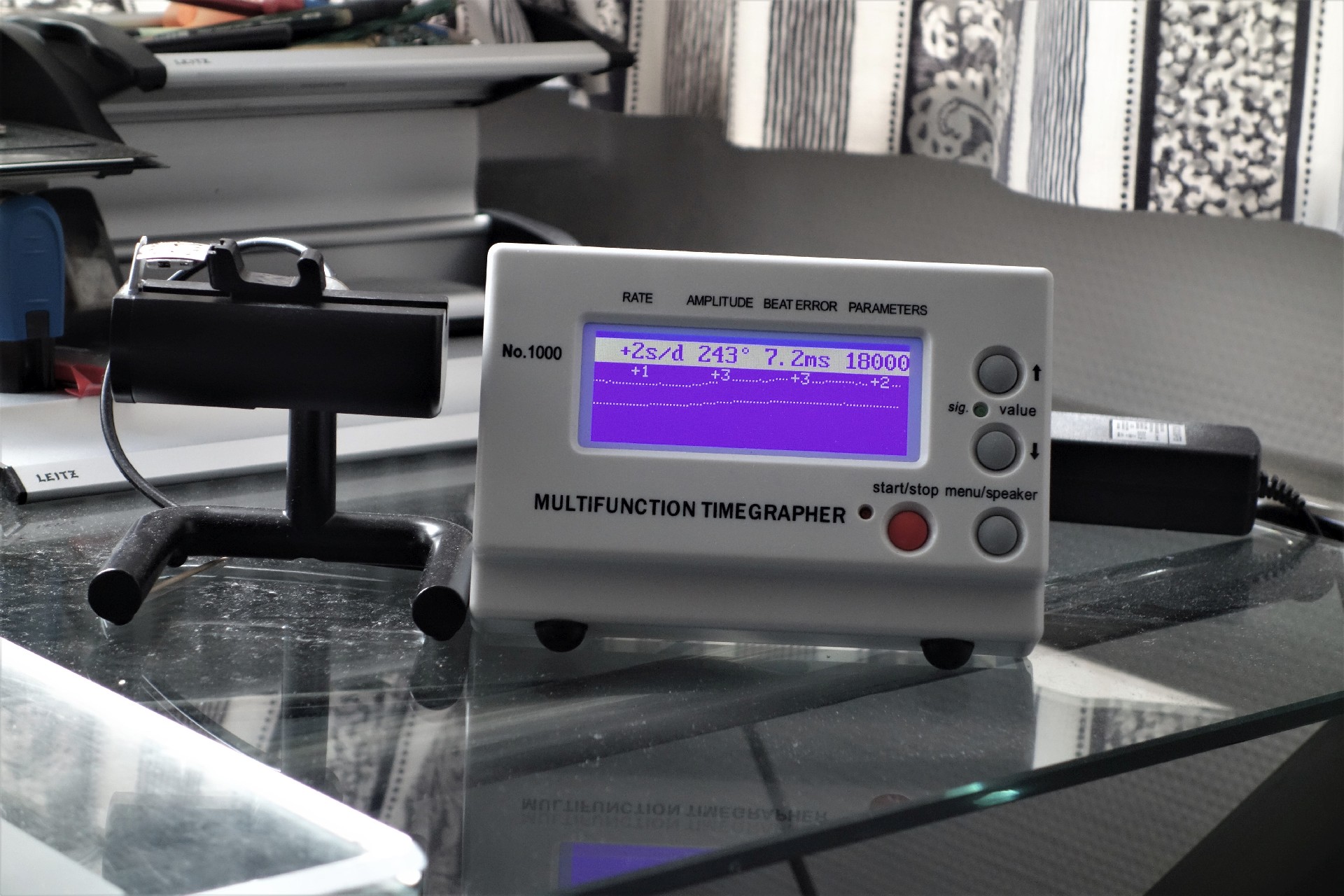 Weißes elektronisches Messgerät zur Überprüfung von mechanischen Uhren mit digitalem Display.