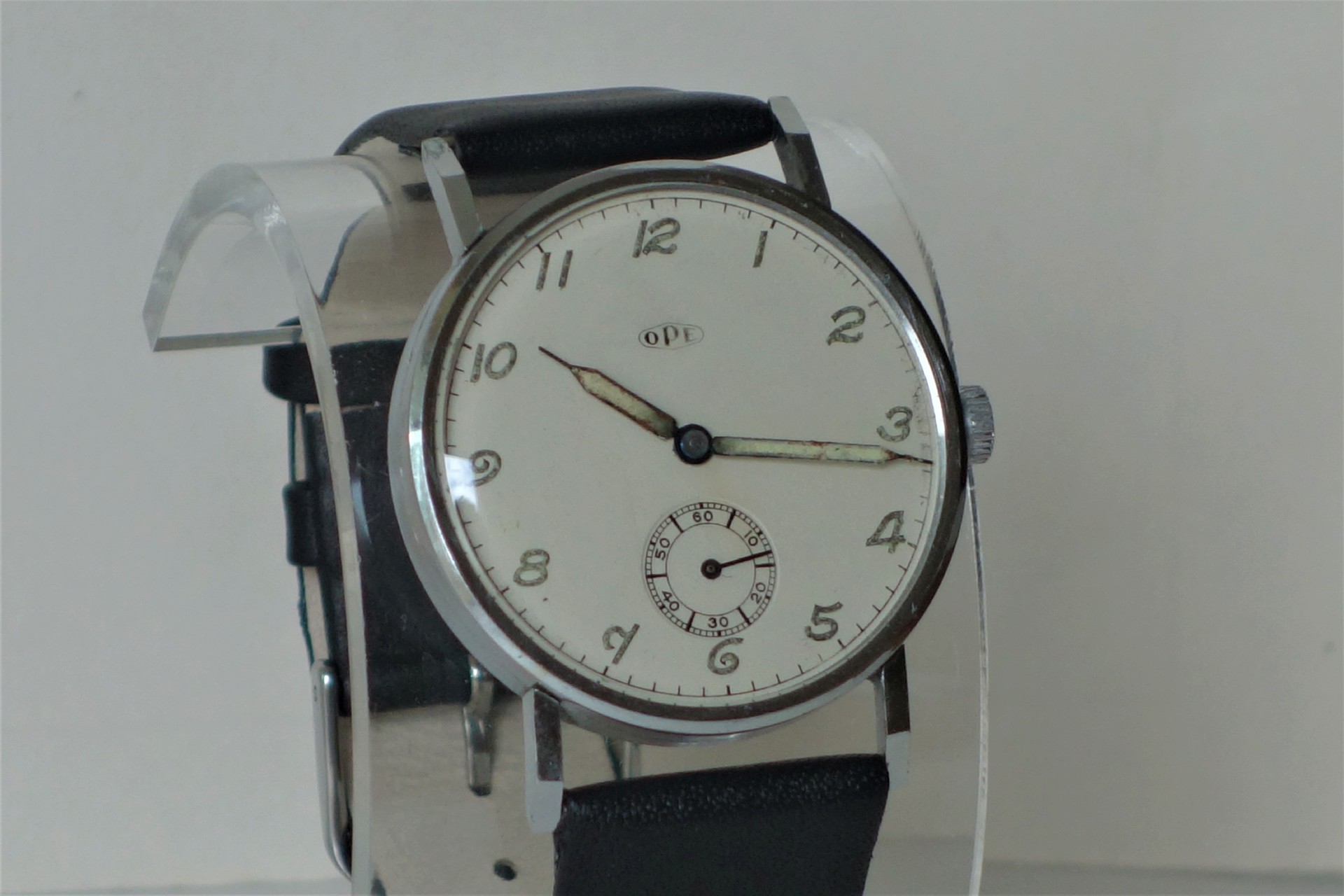 Analoge Armbanduhr mit hellem Zifferblatt, schwarzen Ziffern und schwarzem Lederarmband.