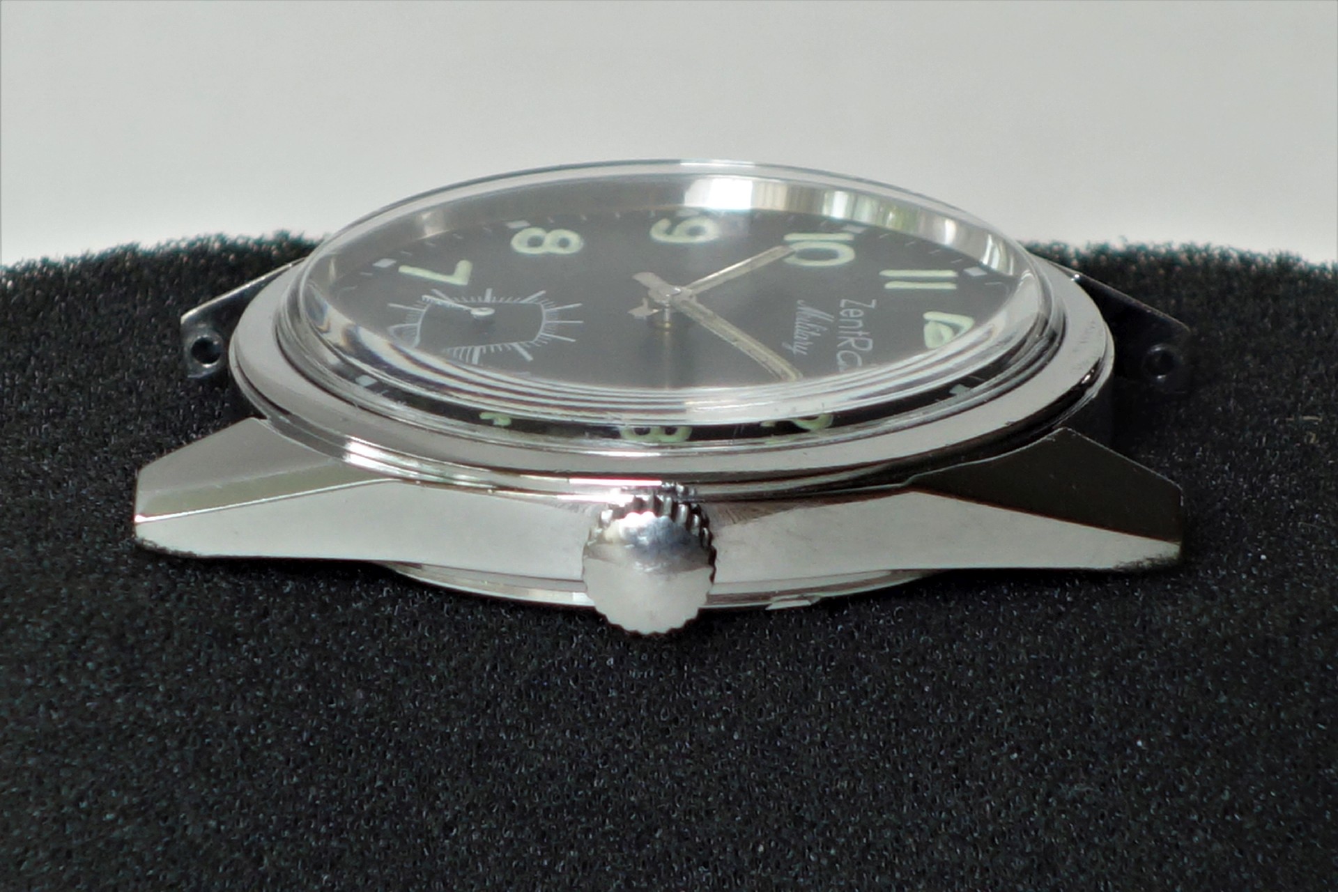 Schwarzes Uhrgehäuse mit silberfarbener Krone und schwarzem Zifferblatt.