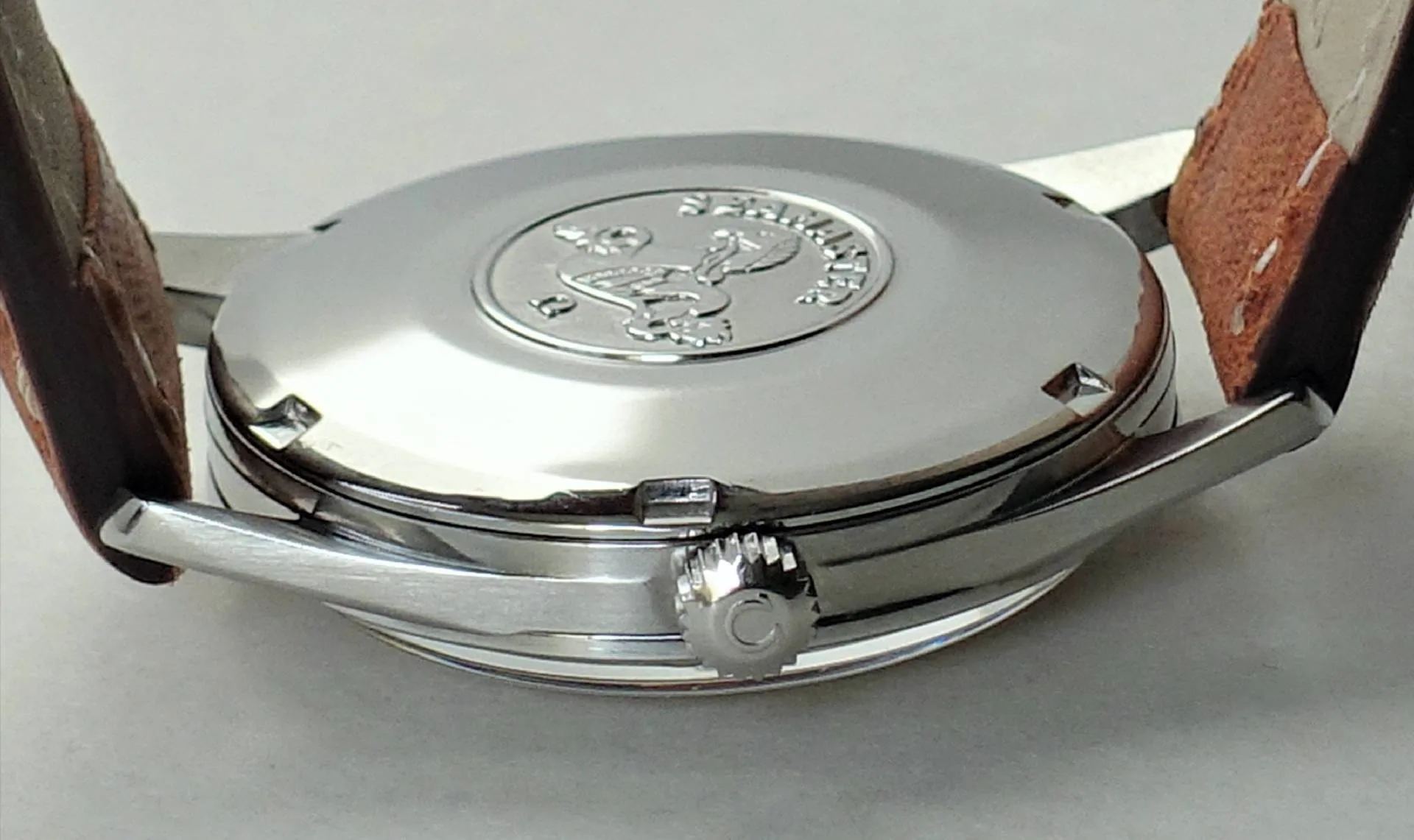 Uhrboden silberfarben Silberfarbener Uhrenboden mit Prägung und braunem Lederarmband.