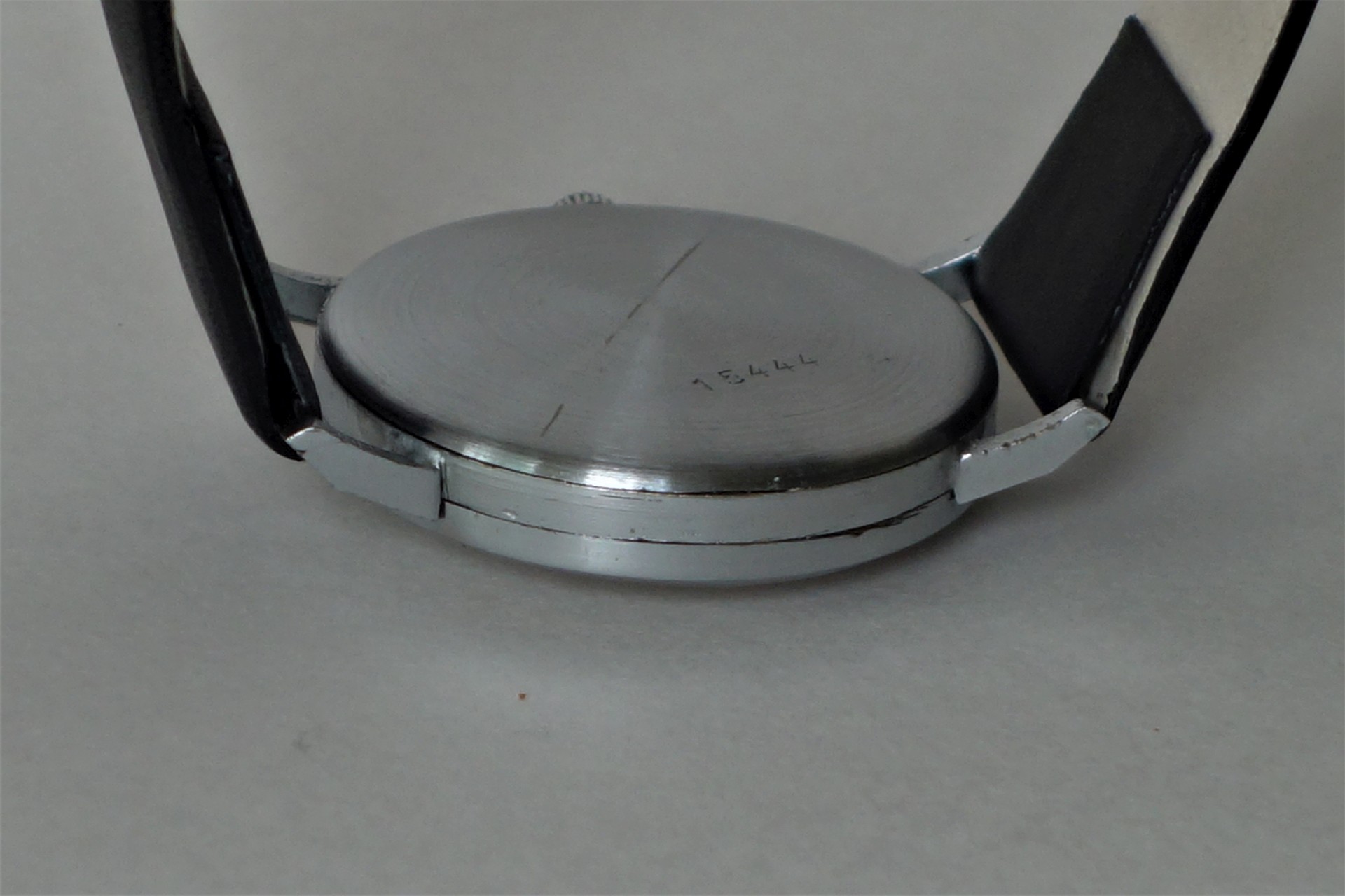 Runder silberfarbener Uhrenboden mit schwarzem Armband.