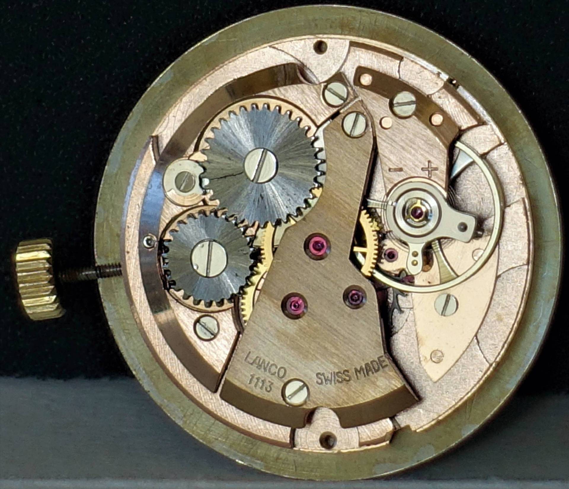 Mechanisches Uhrwerk in goldfarbener Ausführung mit sichtbaren Zahnrädern und Aufzugswelle, Gravur "LANCO 1113 SWISS MADE".