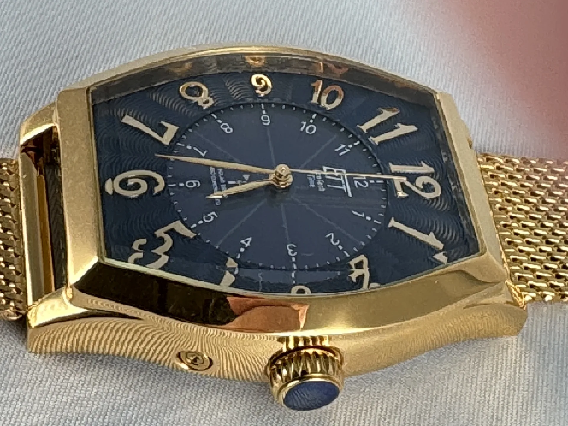 Goldfarbene Armbanduhr mit blauem Zifferblatt, goldenen Zahlen und Mesh-Armband.
