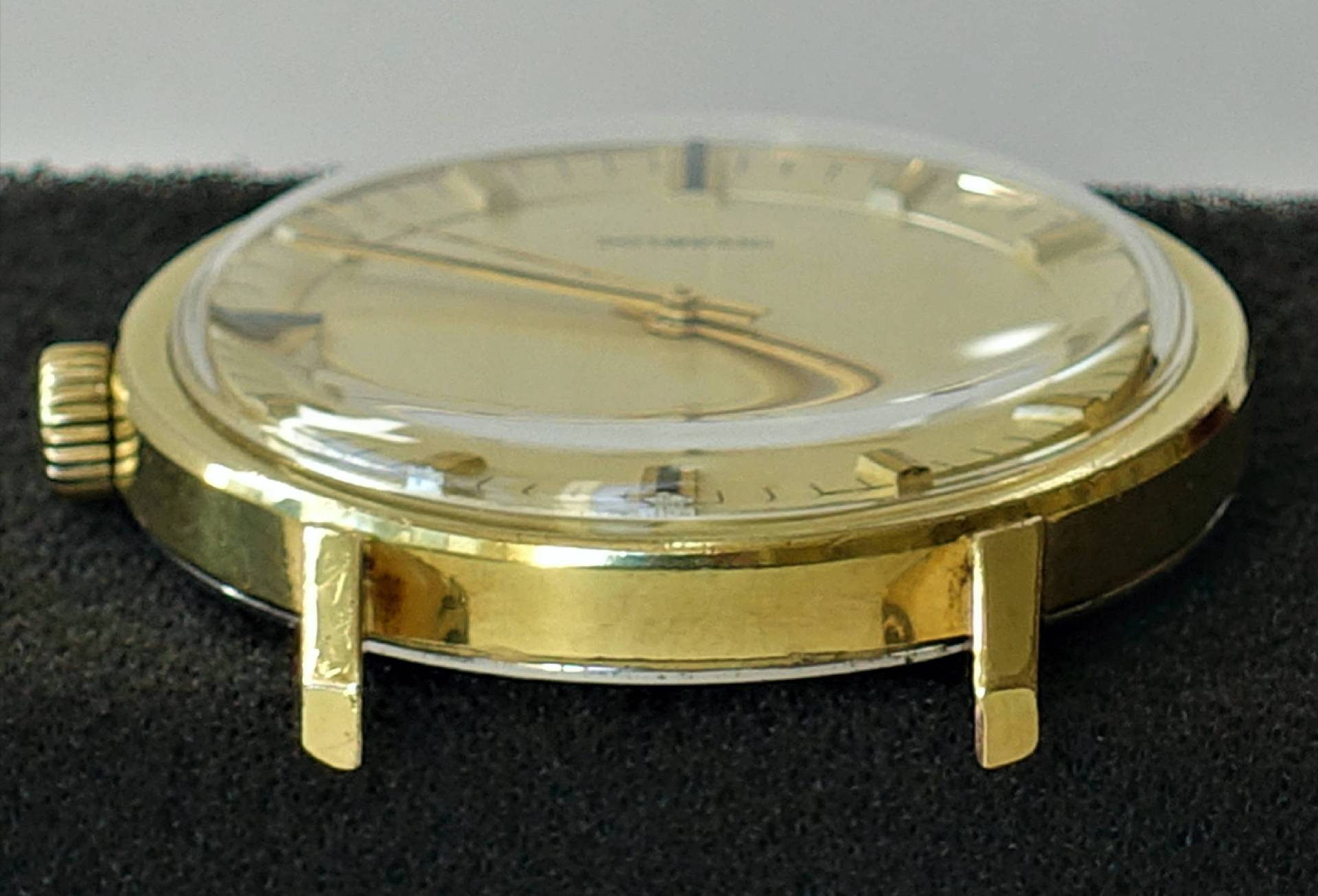 Rundes Uhrgehäuse in goldener Farbe mit Glasabdeckung und Krone, ohne Armband.
