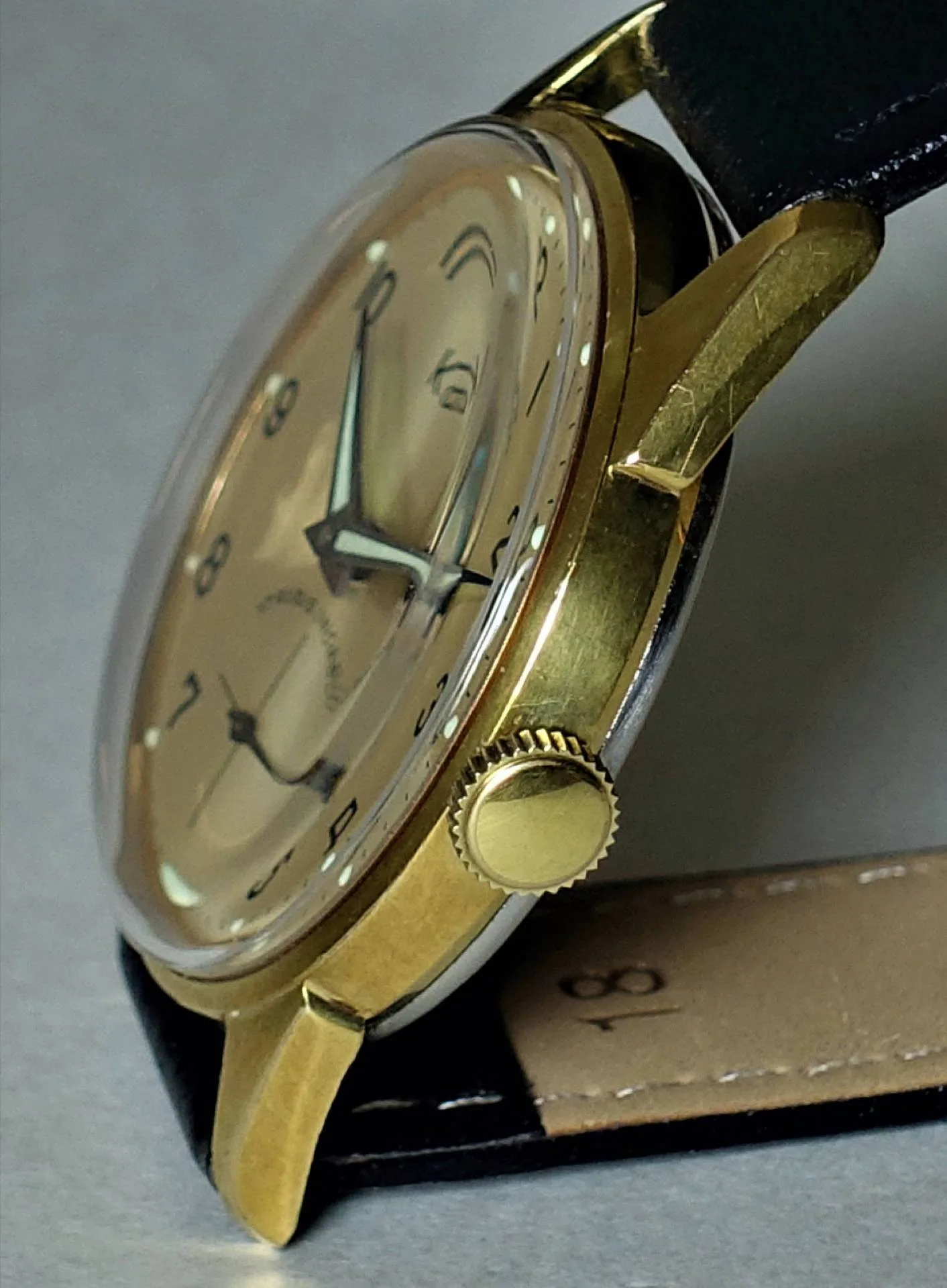 Armbanduhr goldfarben Goldfarbene Armbanduhr mit schwarzem Lederarmband und hellem Zifferblatt.