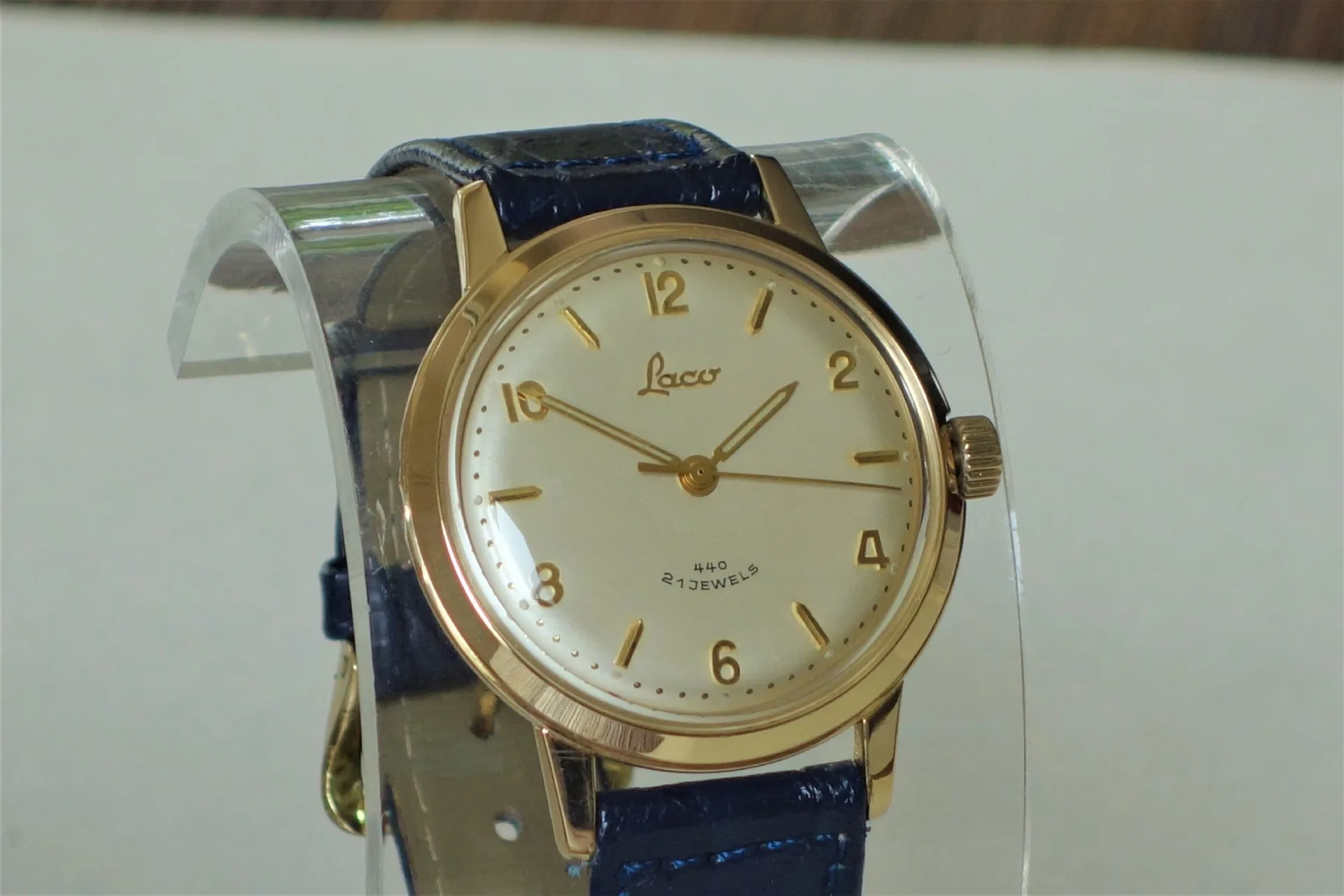Goldfarbene Armbanduhr mit hellem Zifferblatt und blauem Armband.
