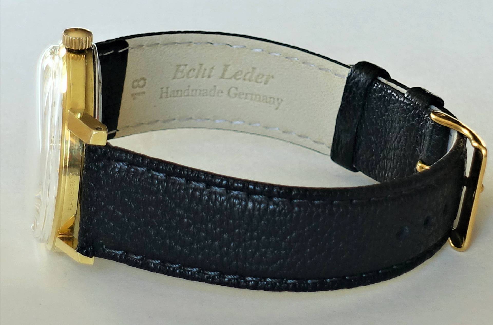 Schwarze Armbanduhr mit goldfarbenem Gehäuse und Schnalle.