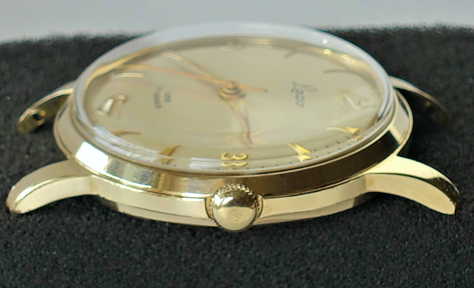 Goldfarbene Armbanduhr mit hellem Zifferblatt und goldenen Zeigern.