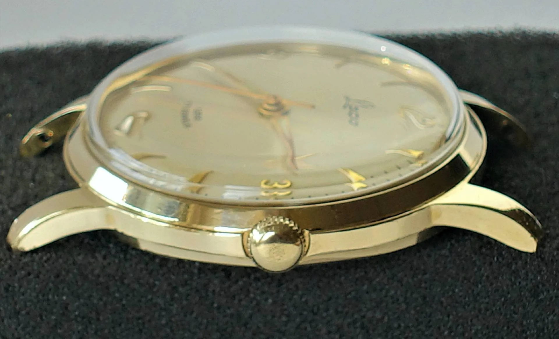 Goldfarbene Armbanduhr mit hellem Zifferblatt und goldenen Zeigern.