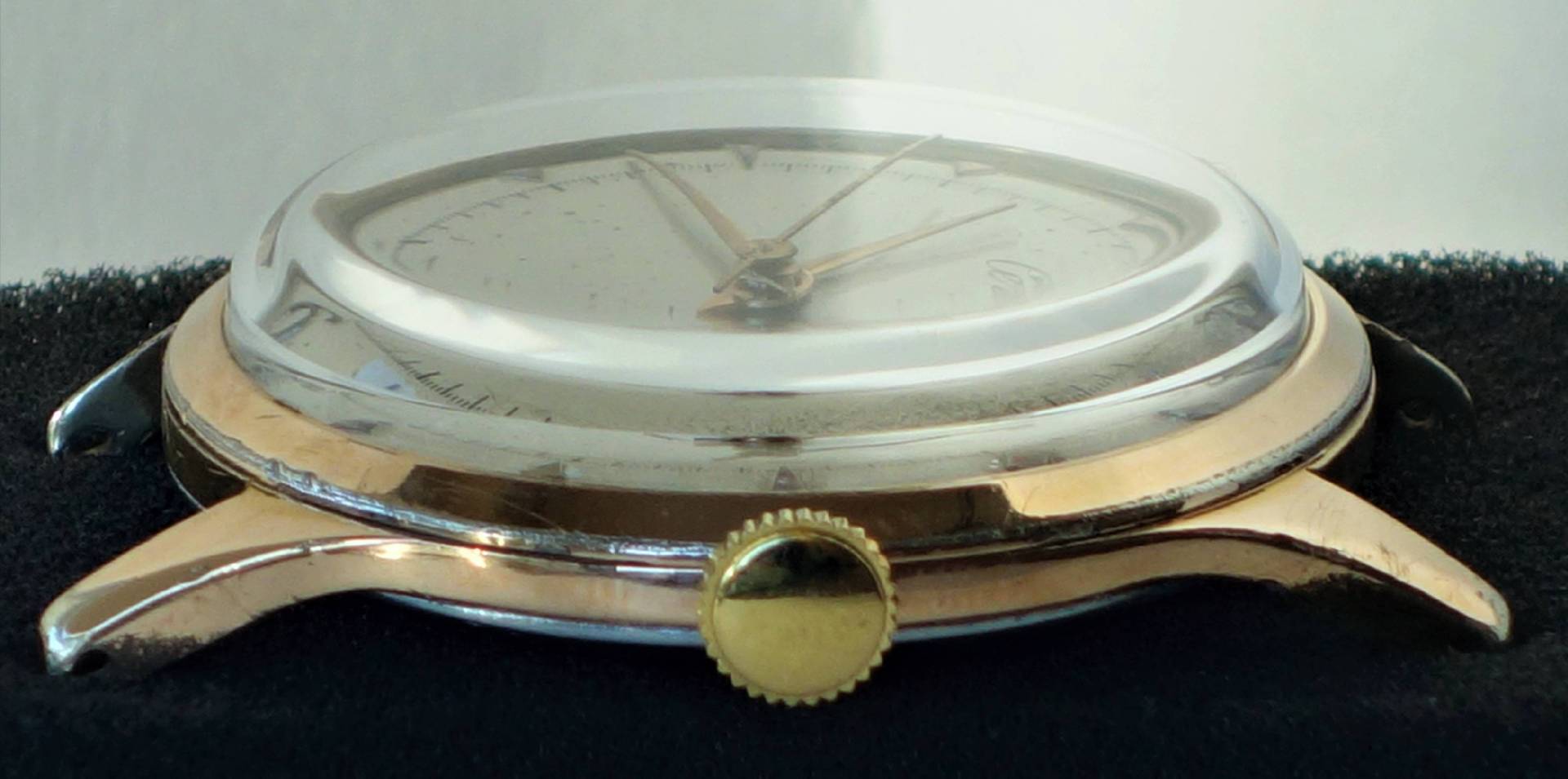 Gehäuse einer goldfarbenen Armbanduhr mit transparentem Uhrglas und goldfarbener Krone.