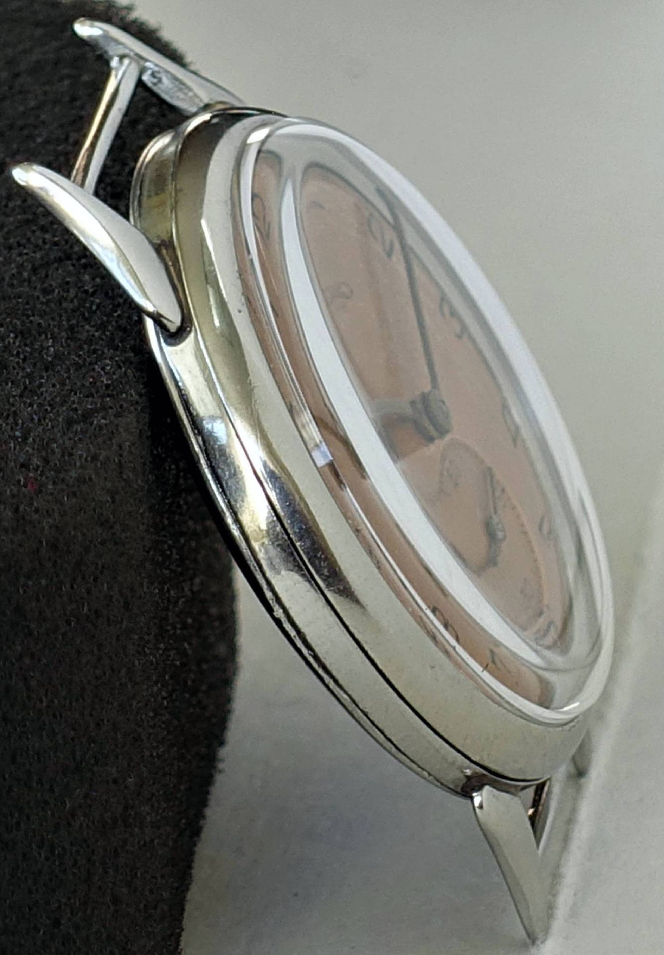 Silberfarbene Armbanduhr mit hellem Zifferblatt und schwarzen Zeigern.