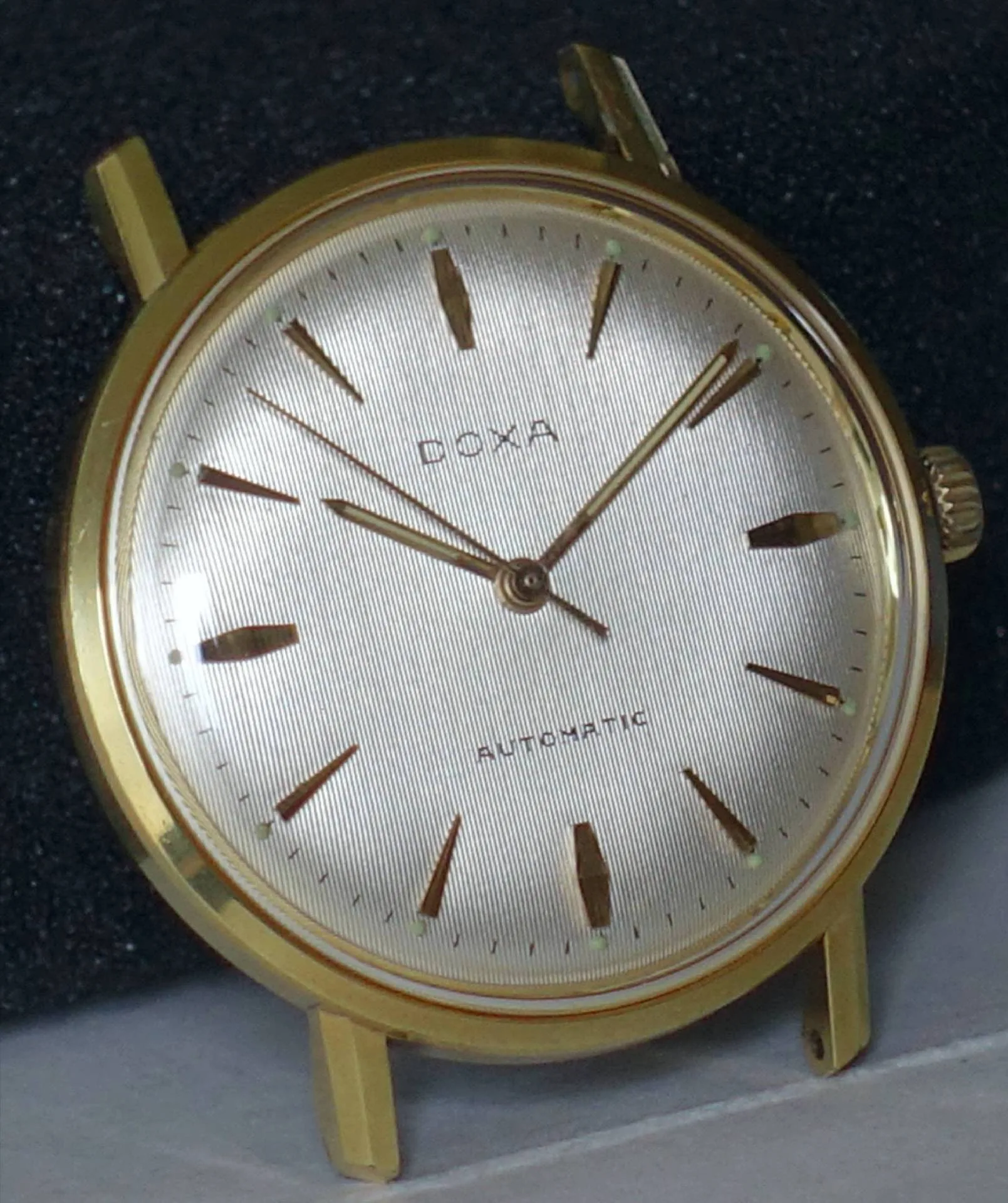 Goldfarbene Doxa Armbanduhr mit hellem Zifferblatt und goldenen Indizes.