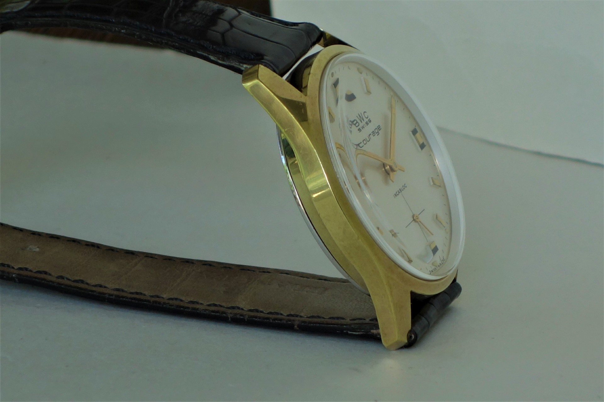 Analoge Armbanduhr mit goldfarbenem Gehäuse und schwarzem Lederarmband.