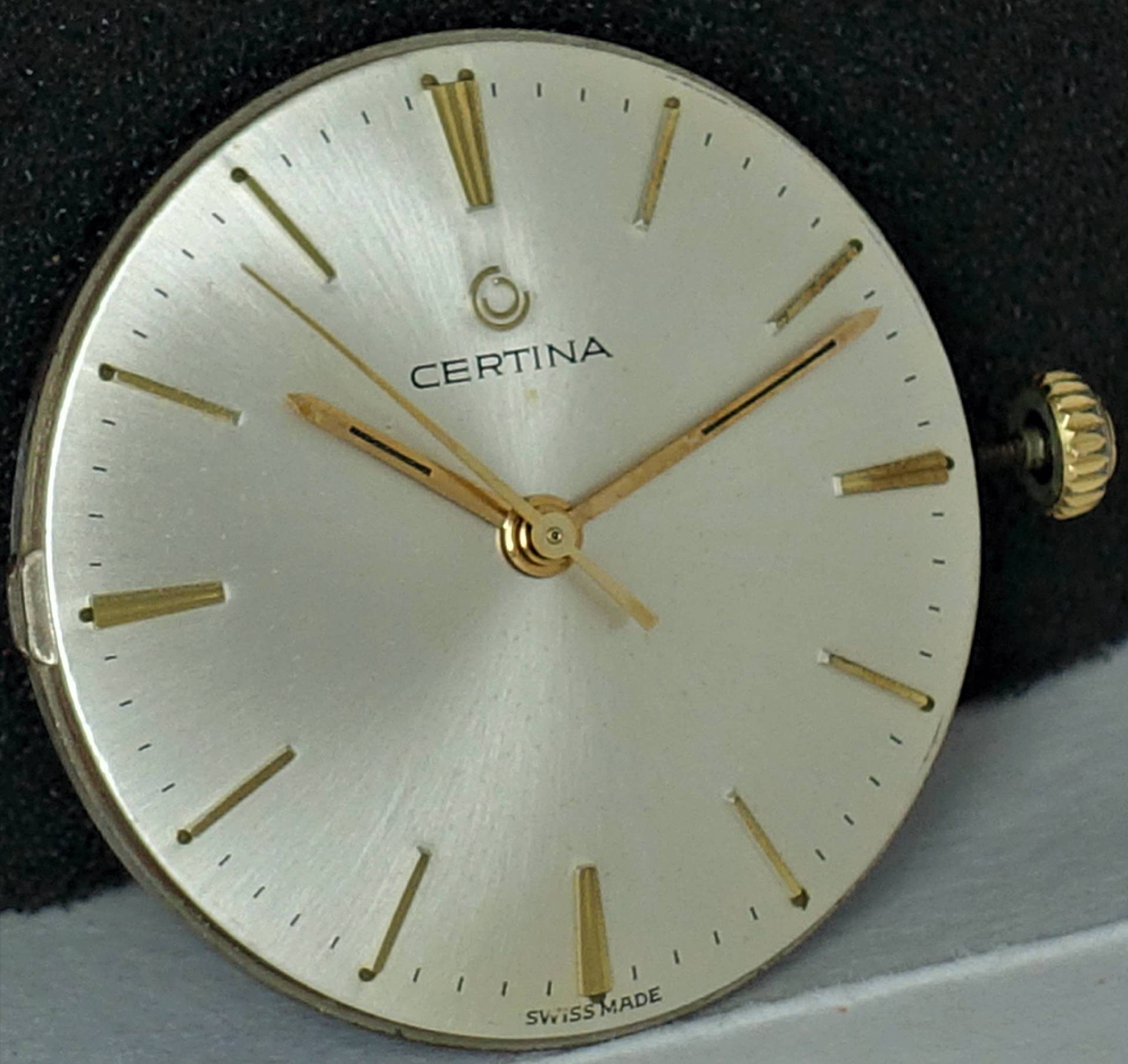 Rundes silberfarbenes Certina Uhrwerk mit goldfarbenen Zeigern und Indizes.
