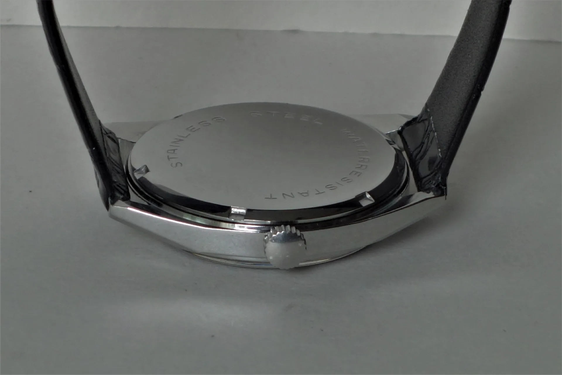 Uhrboden silberfarben Silberfarbener runder Uhrenboden mit seitlicher Krone und schwarzem Armband.