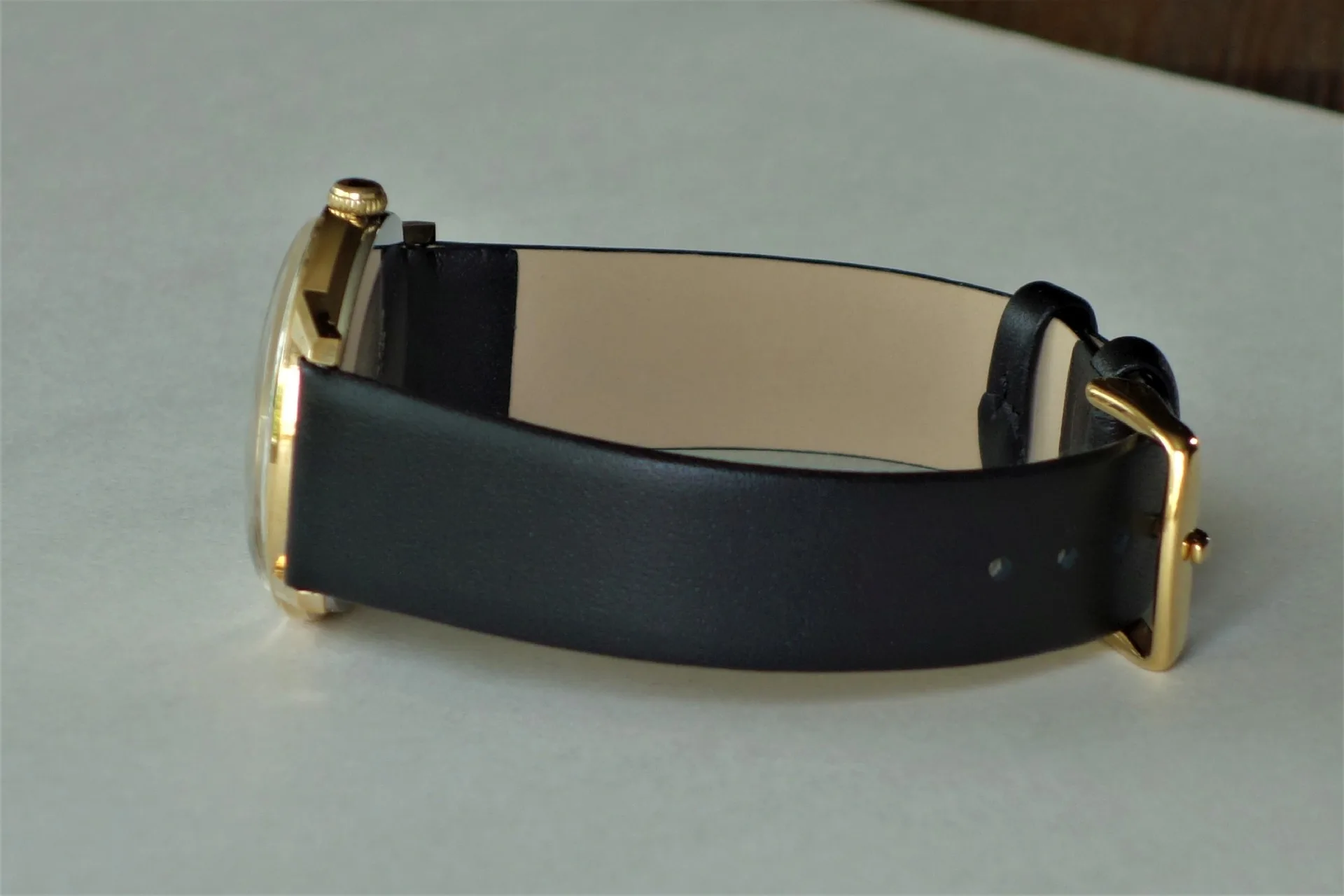 Armbanduhr mit schwarzem Armband und goldfarbener Schließe.