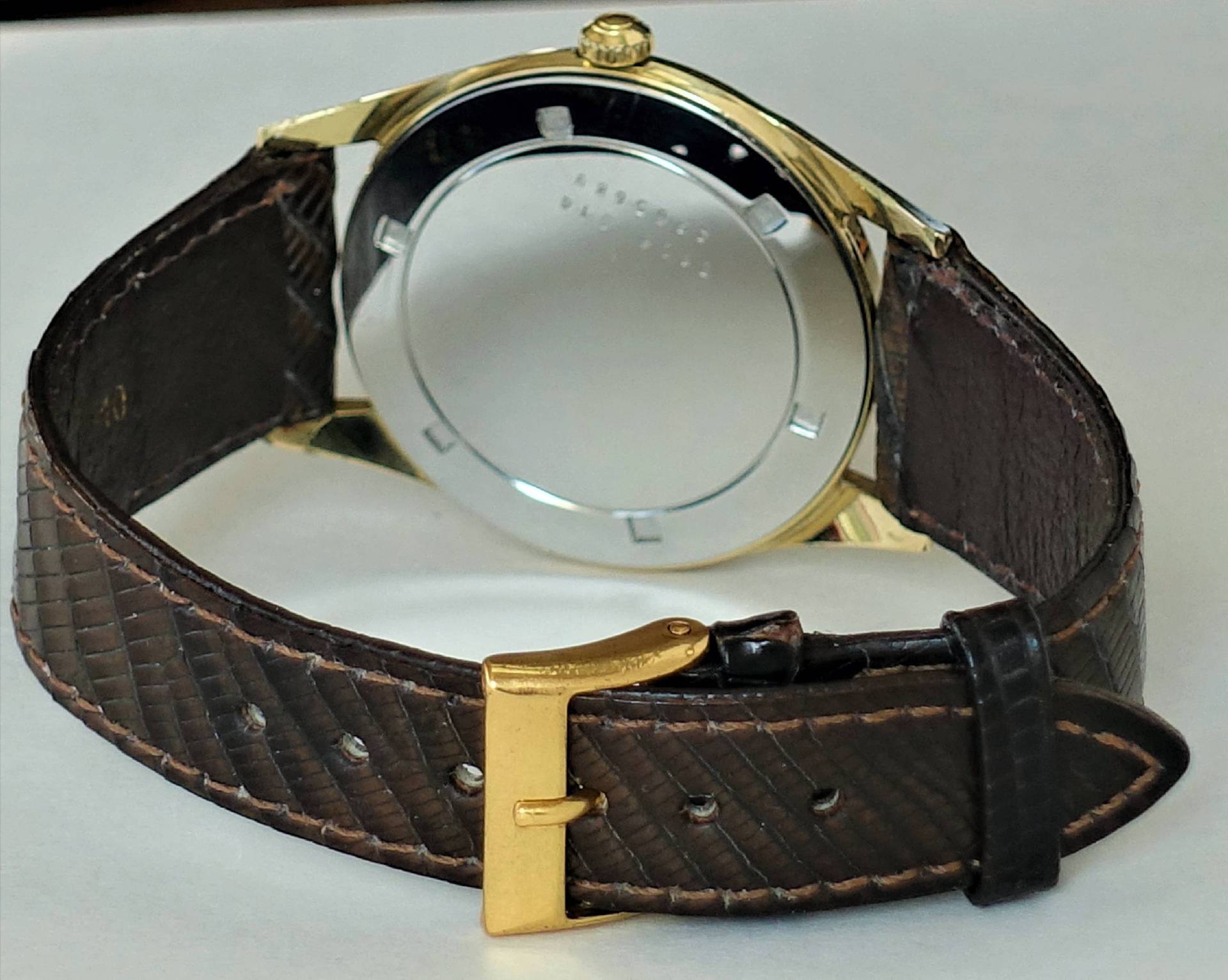 Armbanduhr mit braunem Armband und goldfarbenem Gehäuse, Rückseite sichtbar.