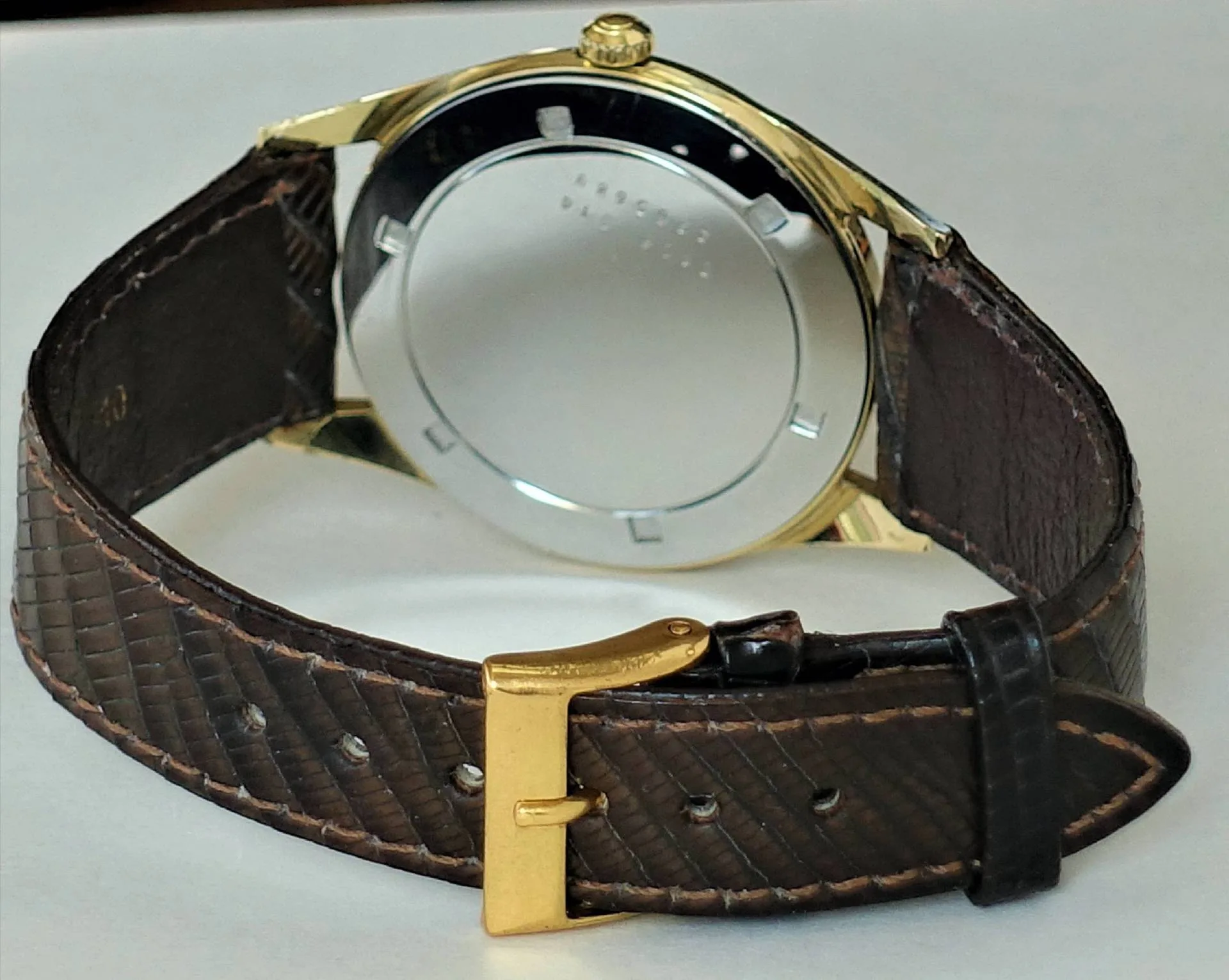 Armbanduhr braun goldfarben Armbanduhr mit braunem Armband und goldfarbenem Gehäuse, Rückseite sichtbar.