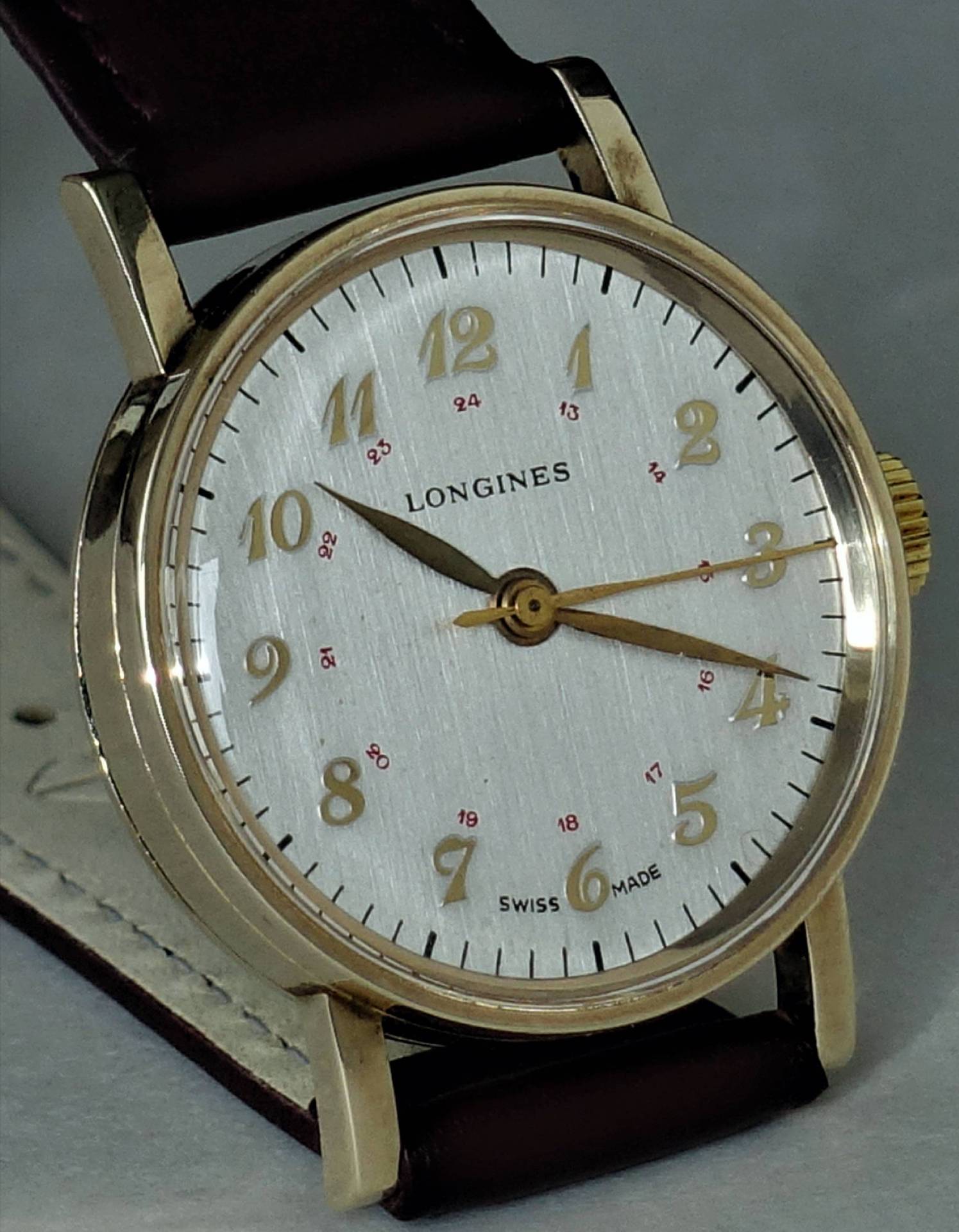 Longines Uhr mit schlichtem Design, goldenen Ziffern und braunem Lederarmband