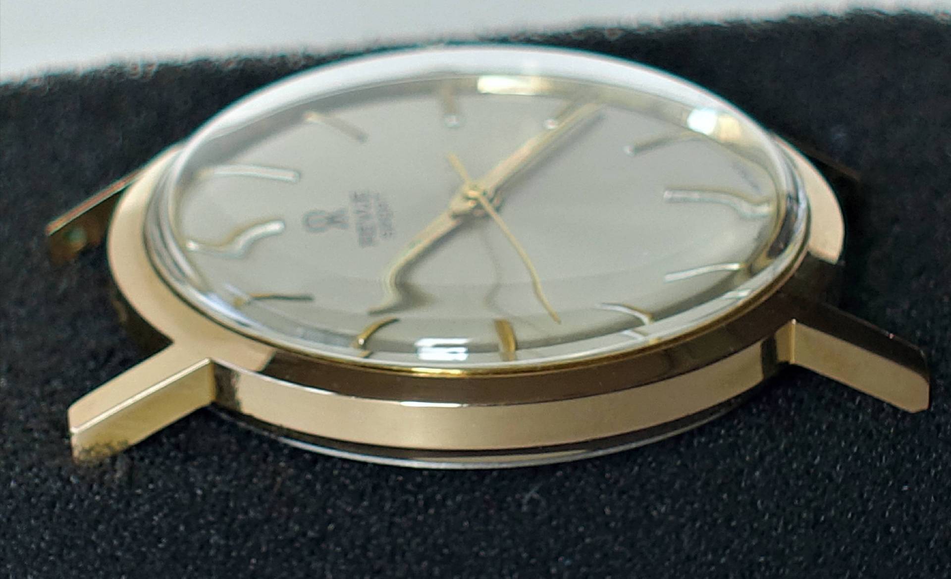 Goldfarbene Armbanduhr mit hellem Zifferblatt und goldenen Zeigern.