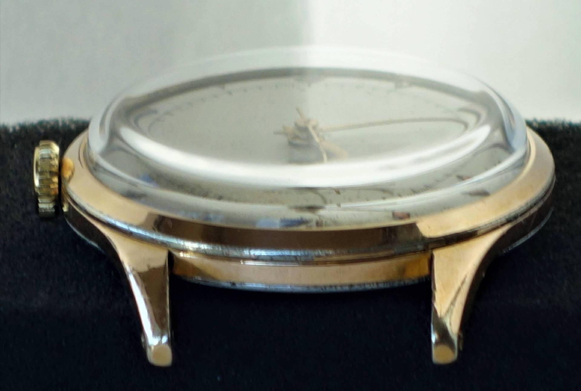 Goldfarbenes Uhrgehäuse mit transparenter Abdeckung und seitlicher Krone.