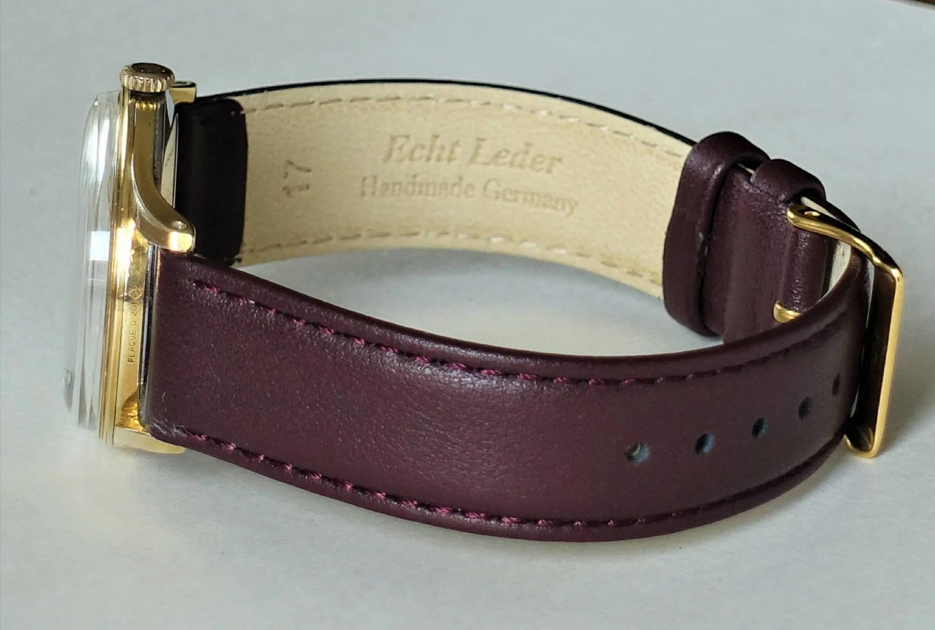 Dunkelrotes Lederarmband für Uhren mit goldfarbener Schließe.