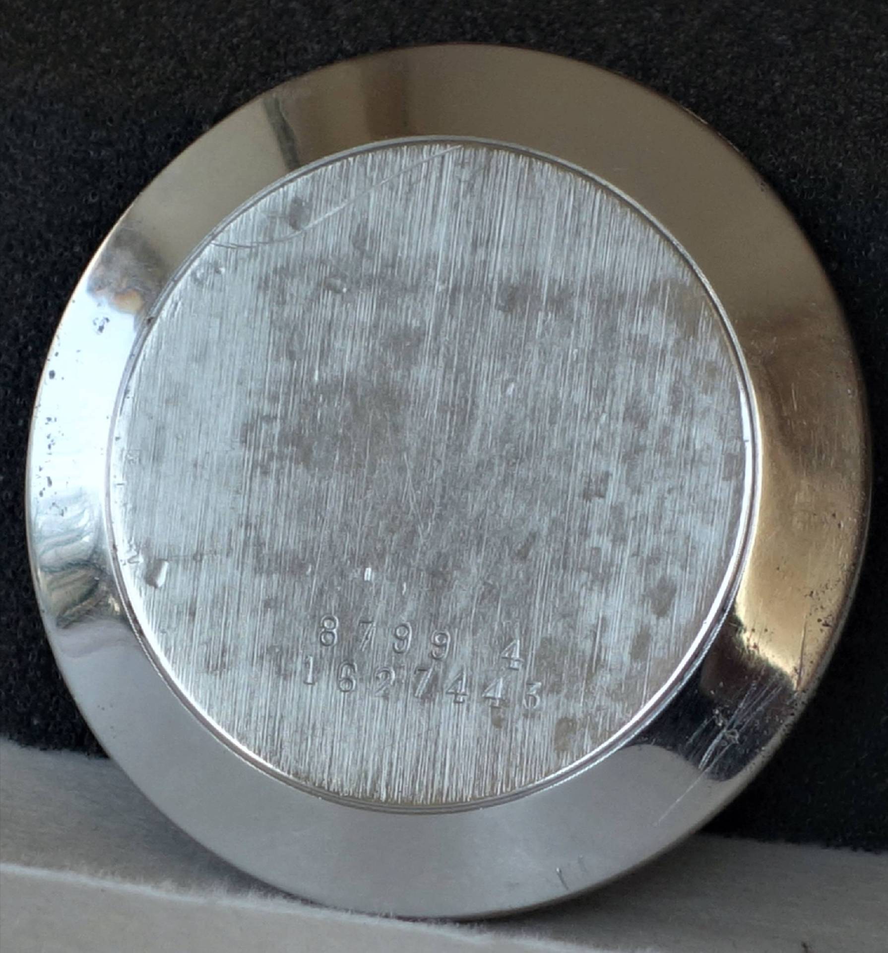 Runder silberfarbener Gehäuseboden für Armbanduhren mit eingravierten Zahlen.