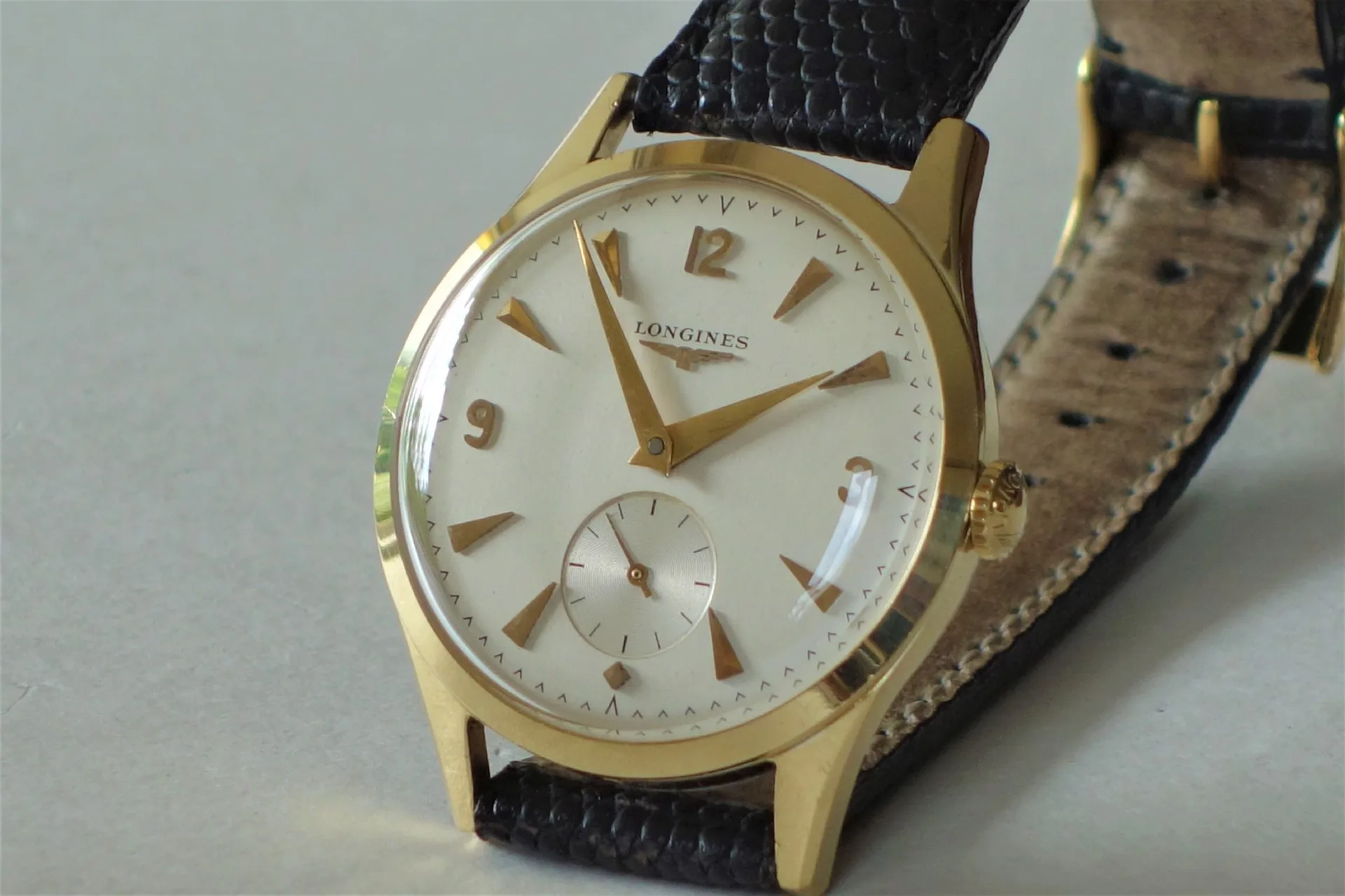 Armbanduhr goldfarben schwarz Klassische Armbanduhr mit goldfarbenem Gehäuse, hellem Zifferblatt und schwarzem Armband.