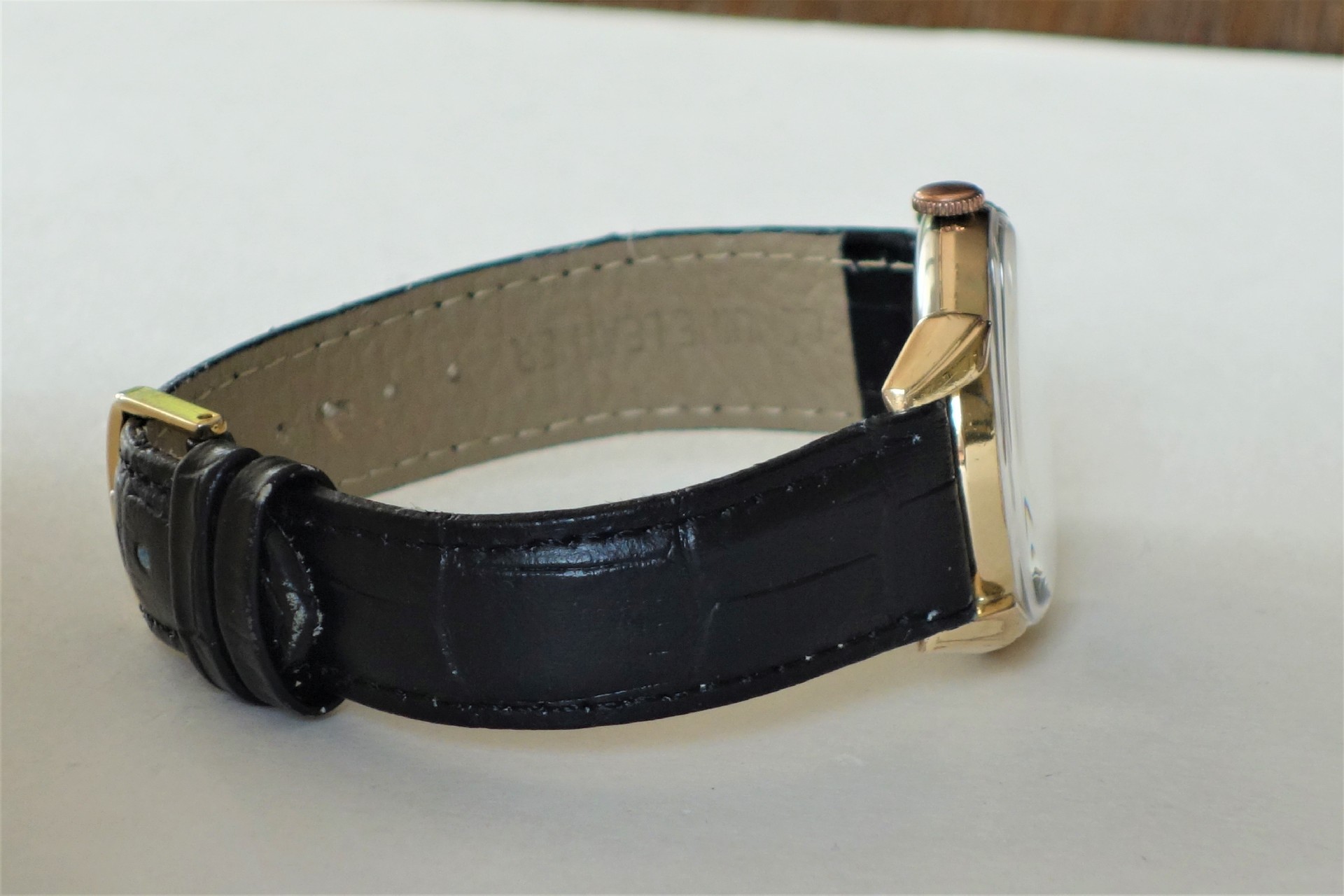 Armbanduhr mit schwarzem Armband und goldfarbenem Gehäuse.