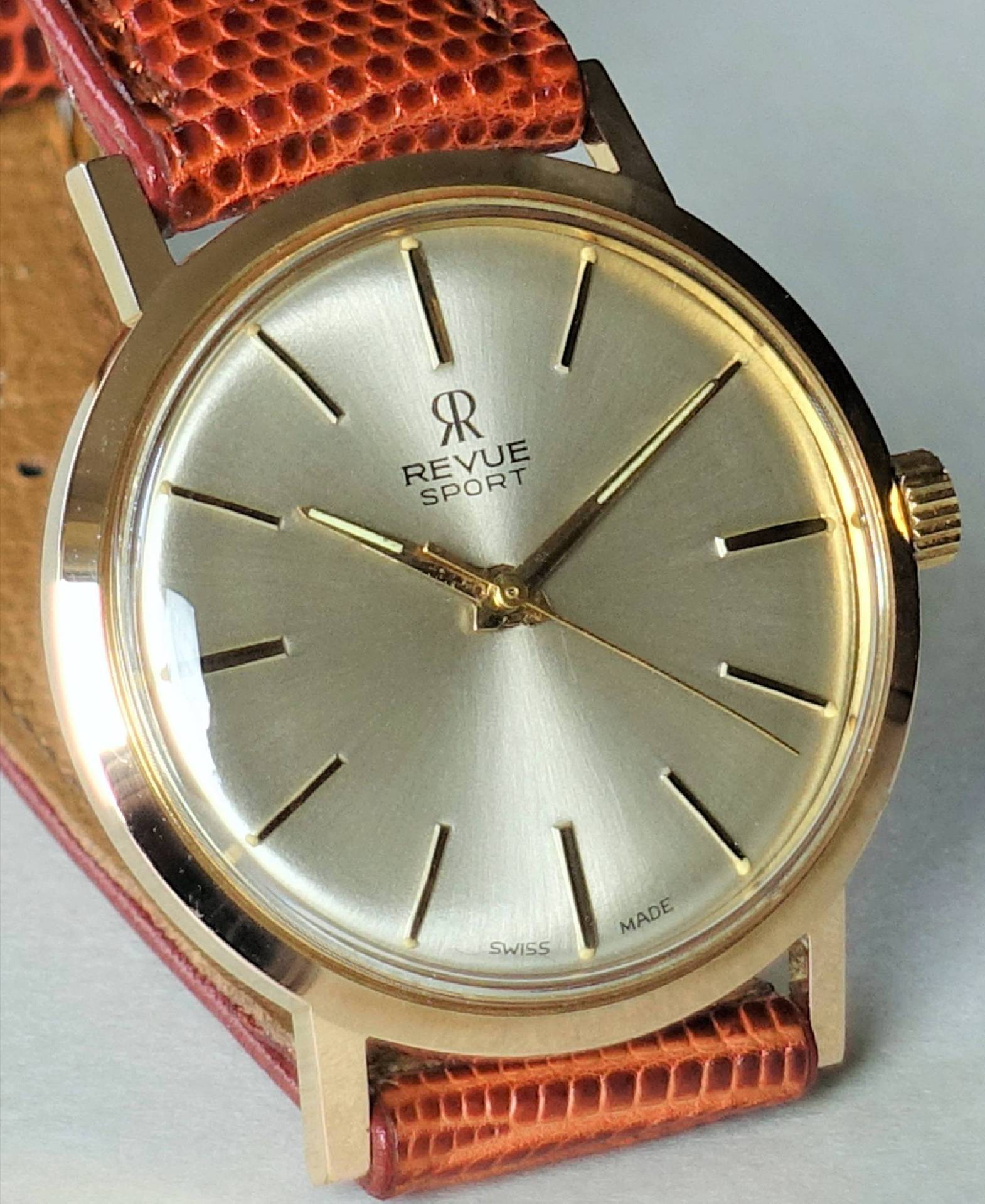 Goldfarbene Armbanduhr mit hellem Zifferblatt und braunem Lederarmband.