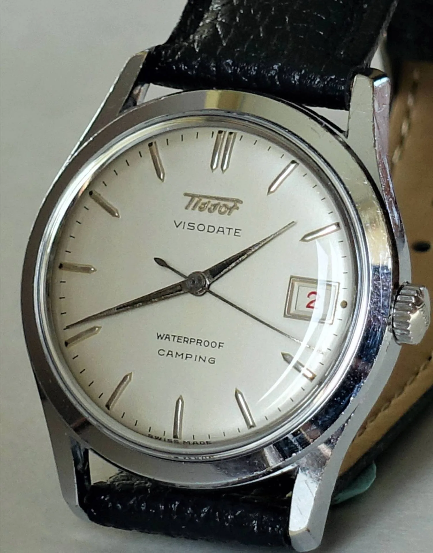 Tissot Visodate Armbanduhr Silberfarbene Armbanduhr mit hellem Zifferblatt, schwarzem Lederarmband und Datumsanzeige.