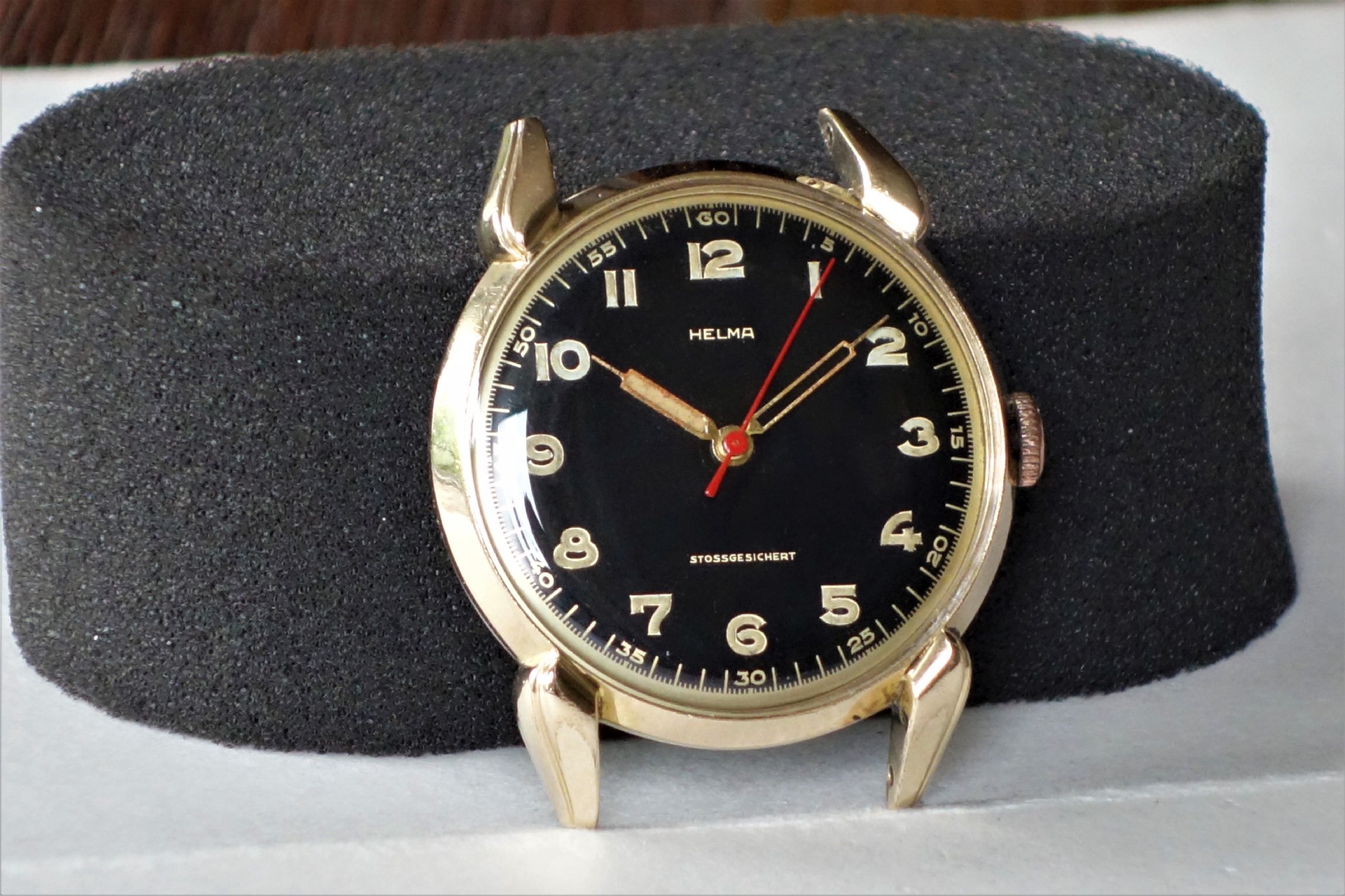 Schwarze Armbanduhr mit goldfarbenem Gehäuse und goldfarbenen Zeigern.