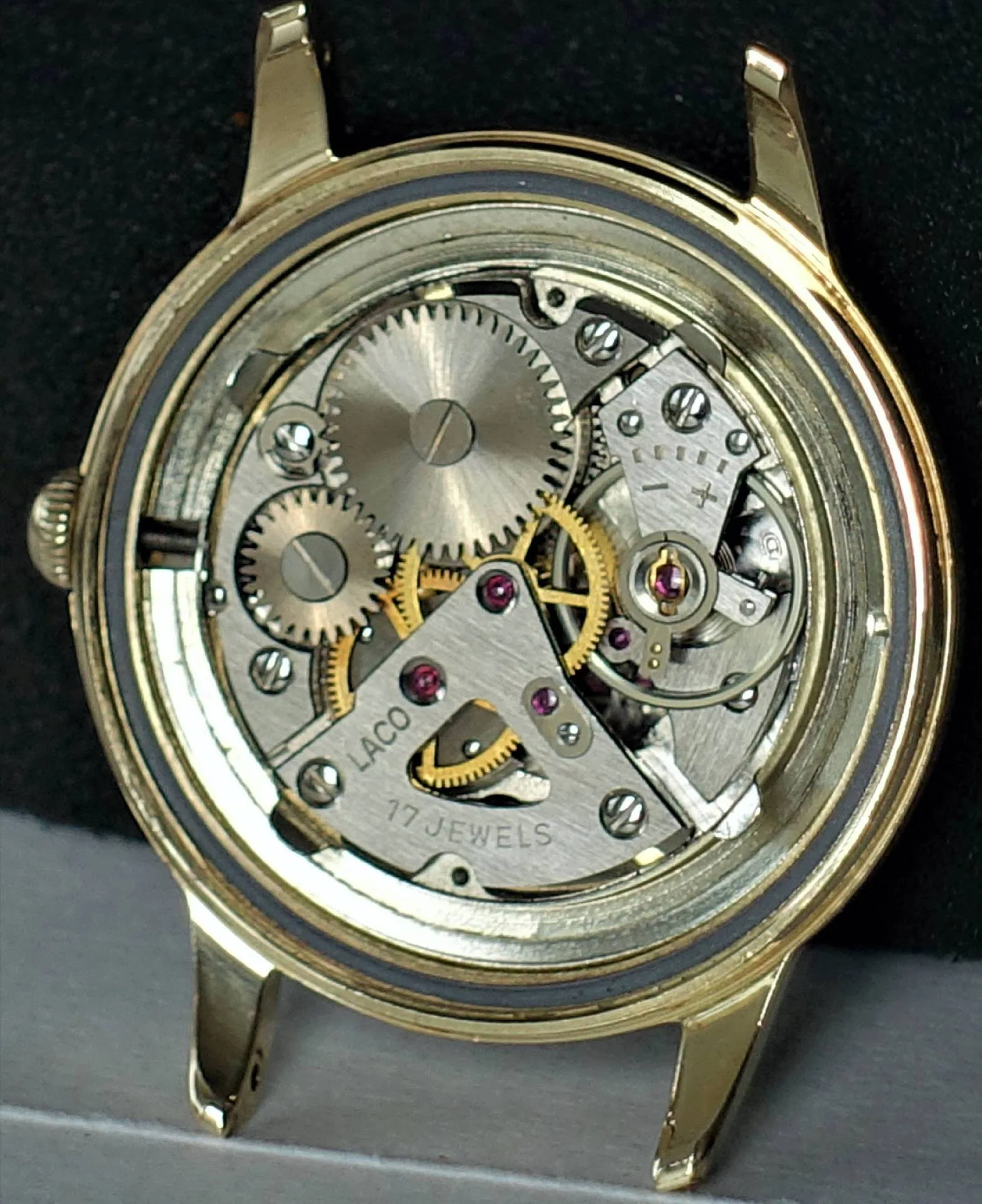 Uhrwerk Laco 17 Jewels Mechanisches Uhrwerk mit sichtbaren Zahnrädern und der Gravur "Laco 17 Jewels" in einem goldfarbenen Gehäuse.