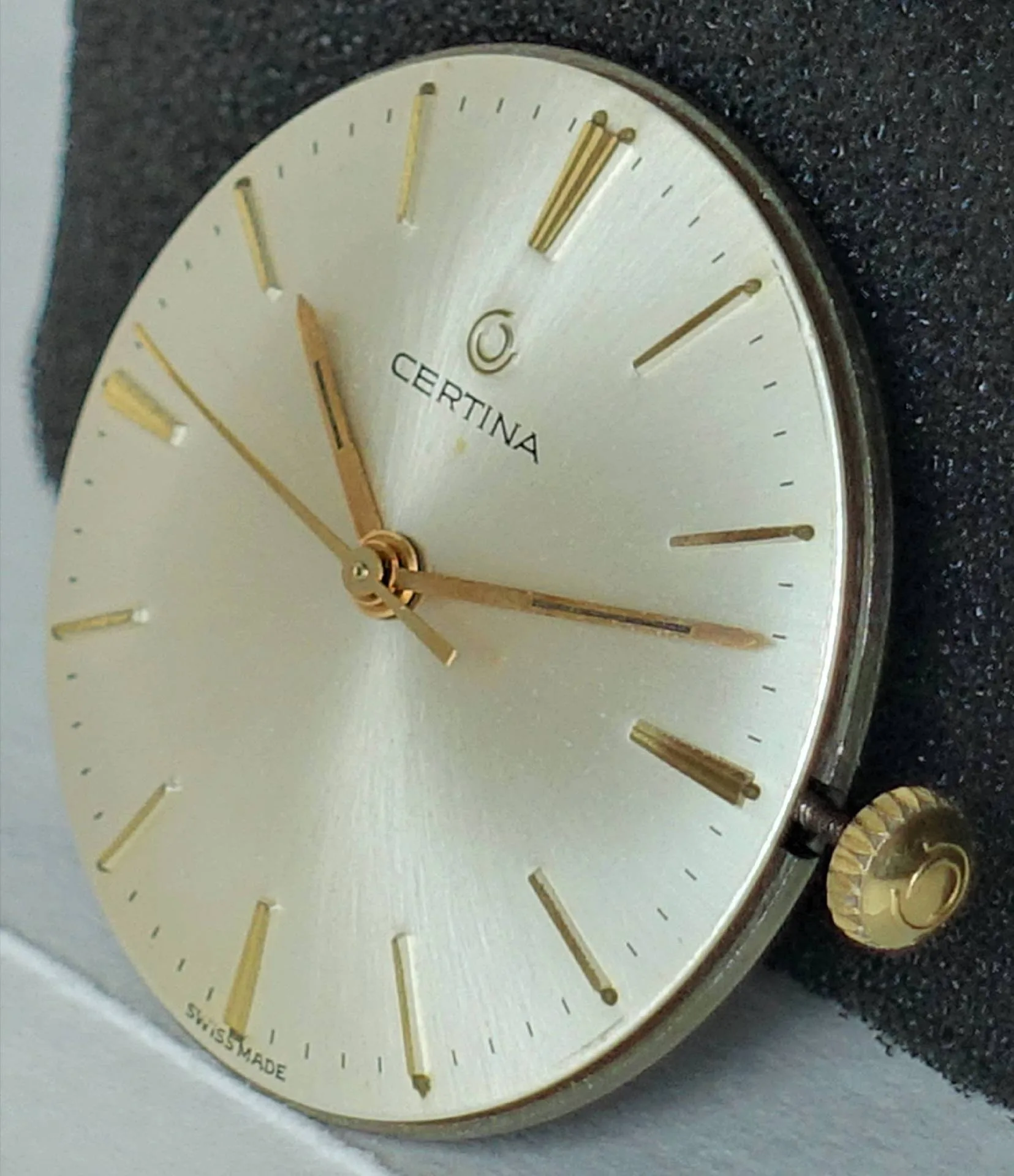 Certina Uhrwerk mit Zifferblatt Silberfarbenes Certina Uhrwerk mit goldfarbenen Zeigern und Indizes sowie seitlicher Krone.