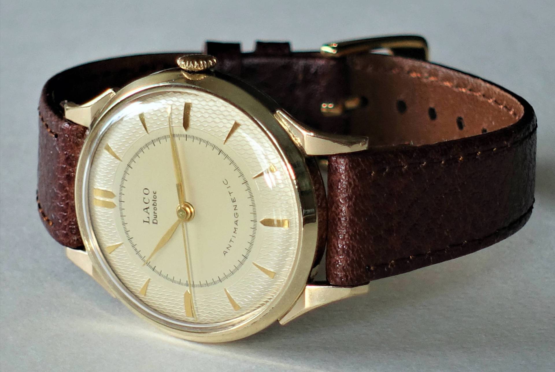Analoge Armbanduhr mit goldfarbenem Gehäuse und braunem Lederarmband.