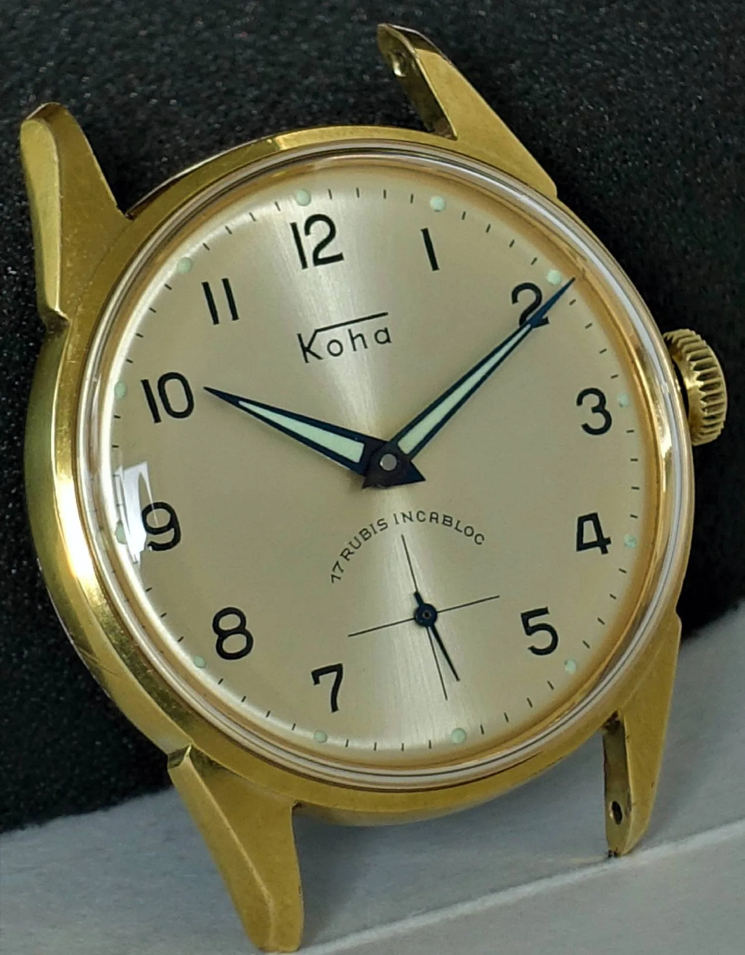 Goldfarbene Armbanduhr mit hellem Zifferblatt und schwarzen Zahlen.