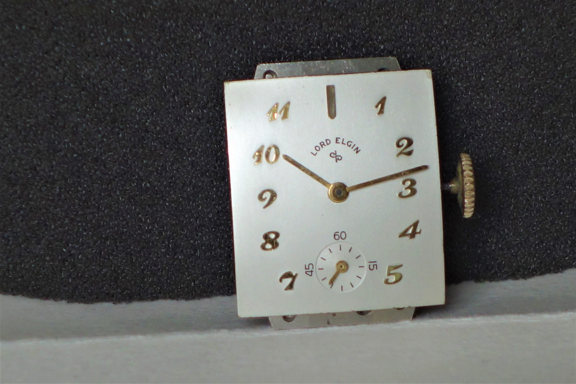 Rechteckiges Uhrwerk mit silberfarbenem Zifferblatt und goldfarbenen Zeigern, Aufschrift "Lord Elgin".